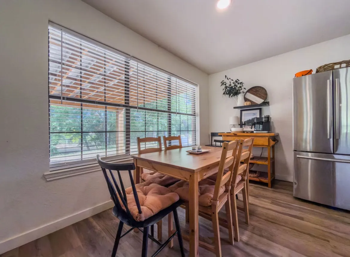 Bright dining area featuring expansive gridded windows with natural light, wood-finish flooring, and a wood dining table