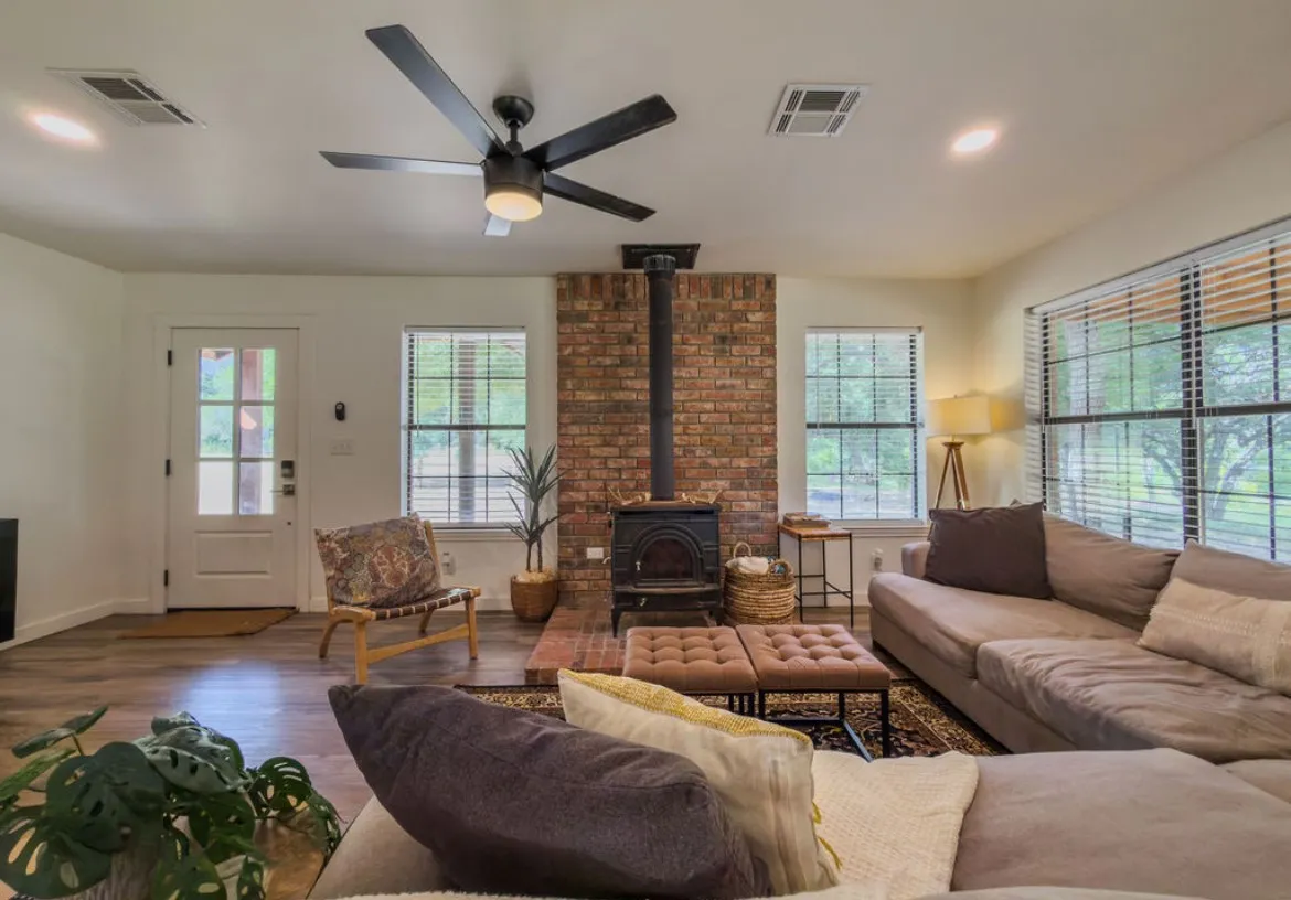 Wood-finish flooring, brick accent wall, ceiling fan, recessed lighting, and multiple windows