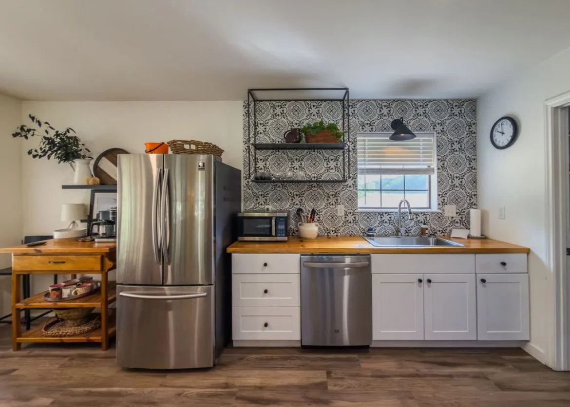 Stainless steel appliances, wood-finish flooring, white cabinetry, patterned backsplash, and wood countertops