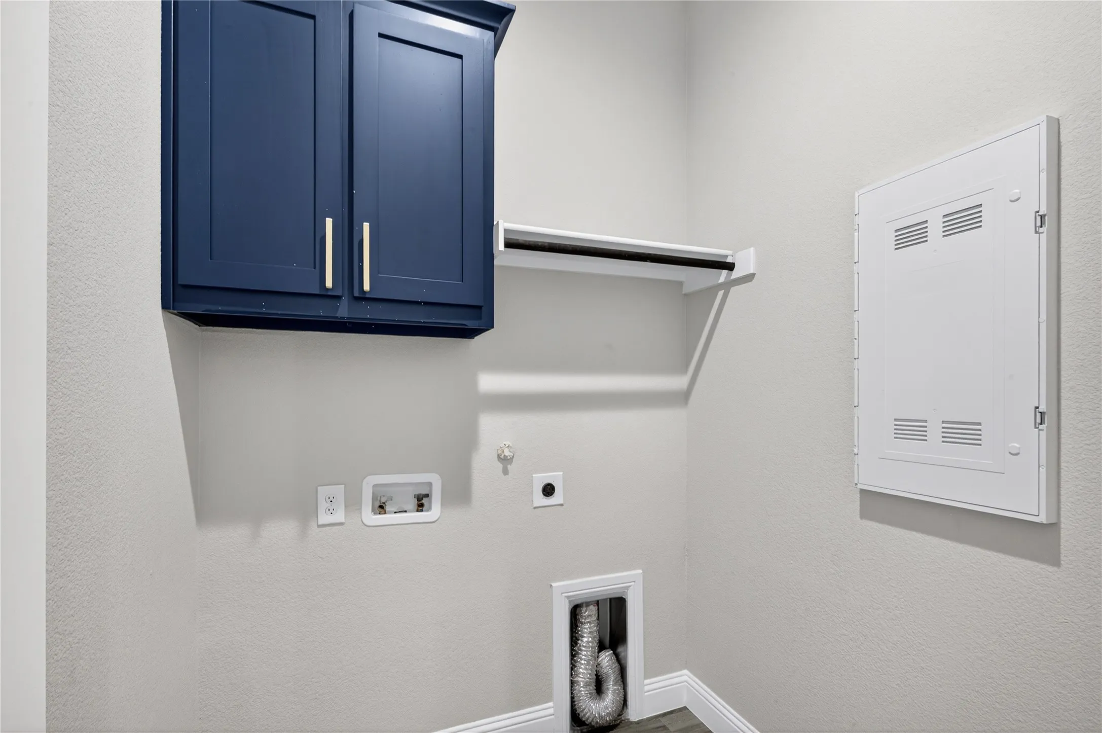 Blue shaker-style cabinetry with brushed nickel hardware, wall-mounted shelving, and wood-finish flooring