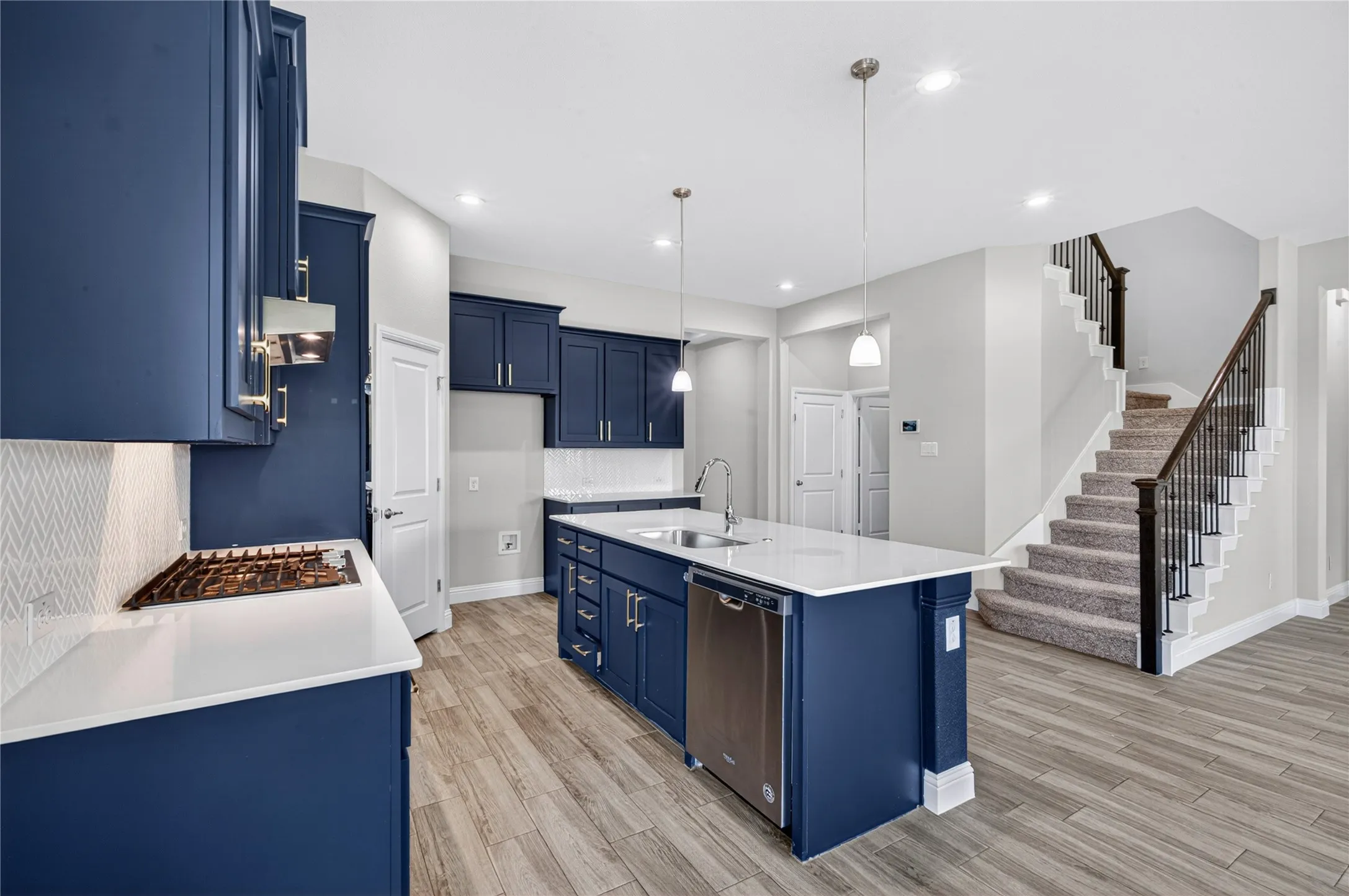 Kitchen featuring blue cabinetry, white countertops, stainless steel appliances, and a central island with sink