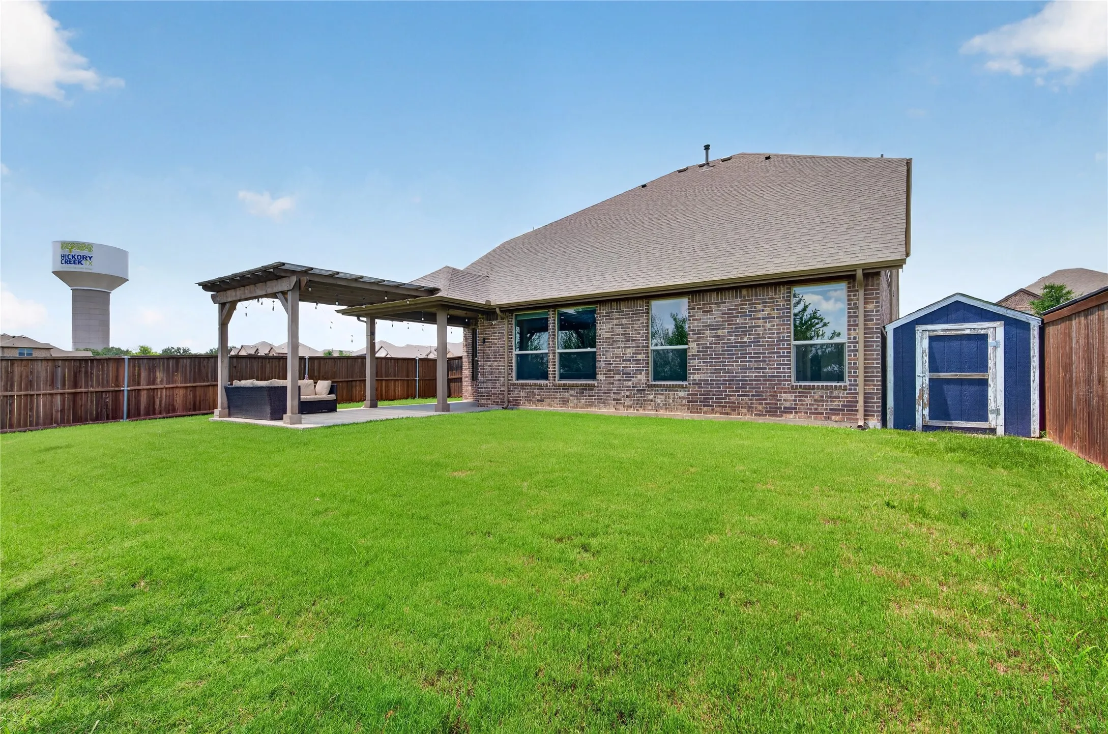 Expansive green lawn with a wood privacy fence and a brick exterior