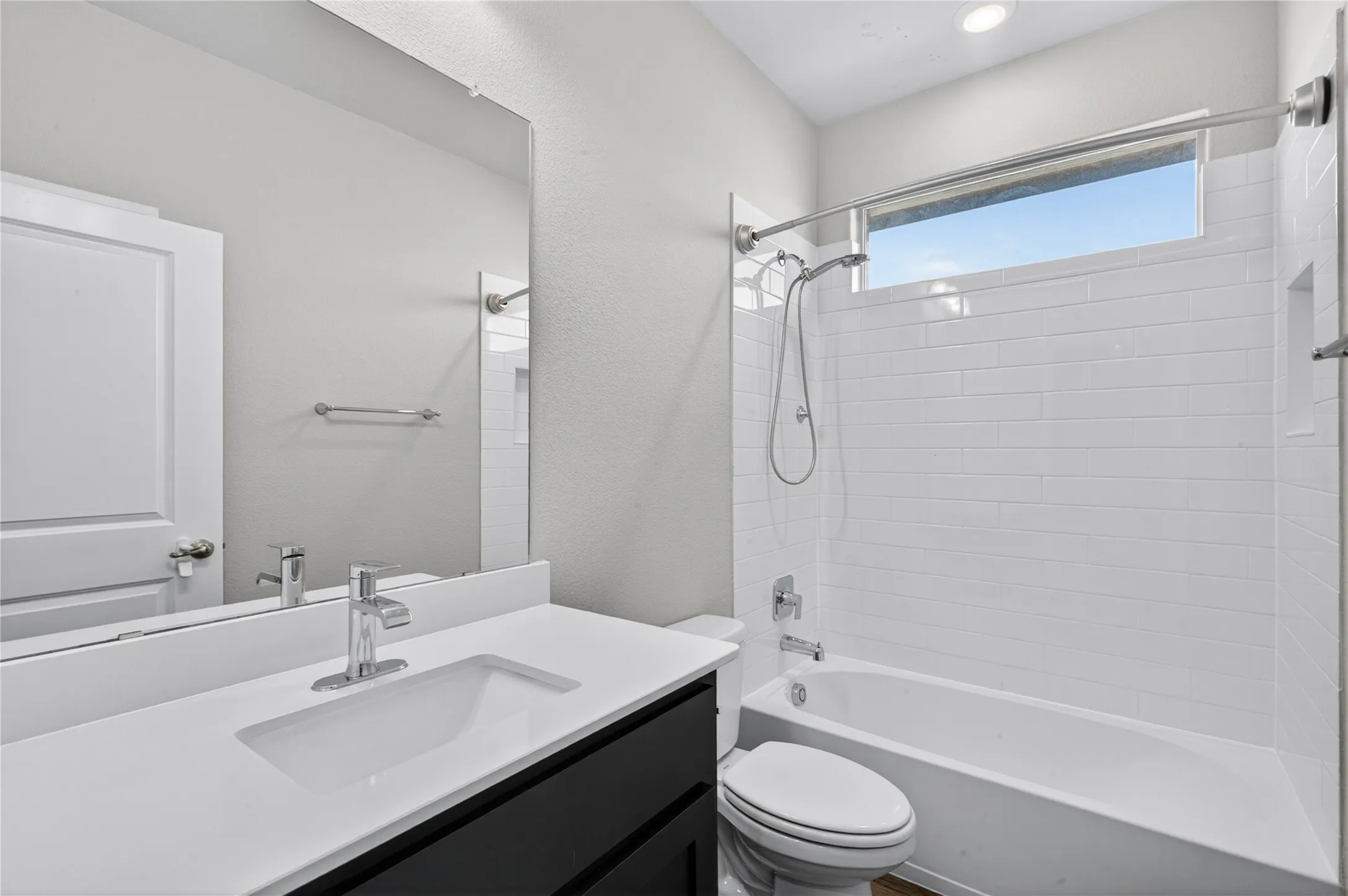 Bathroom featuring a white subway tile shower surround, shower/tub combination, sleek vanity with an integrated sink, and contemporary chrome fixtures