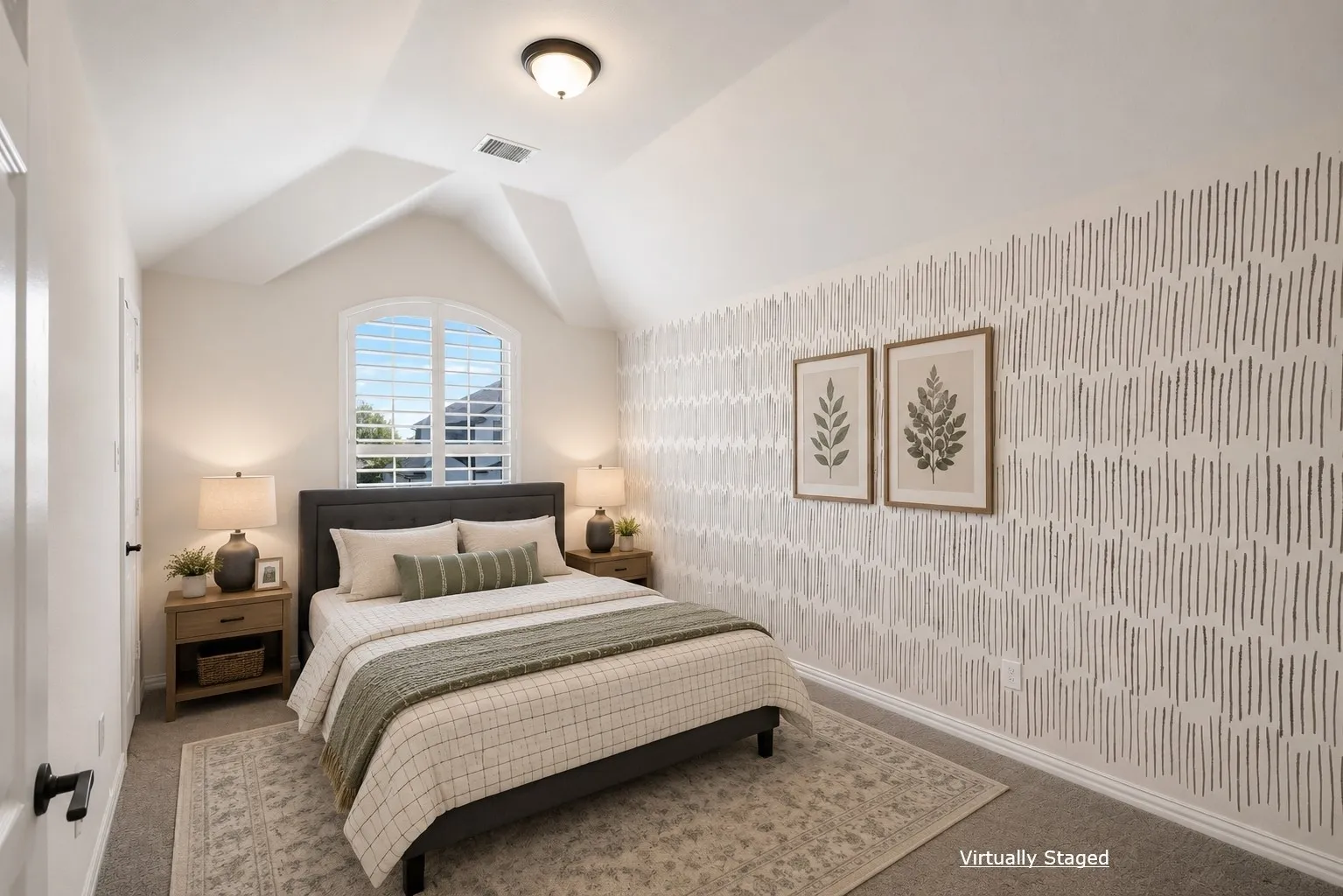 Vaulted ceiling with flush-mount lighting, arched window with plantation shutters, patterned accent wall, and neutral carpeting