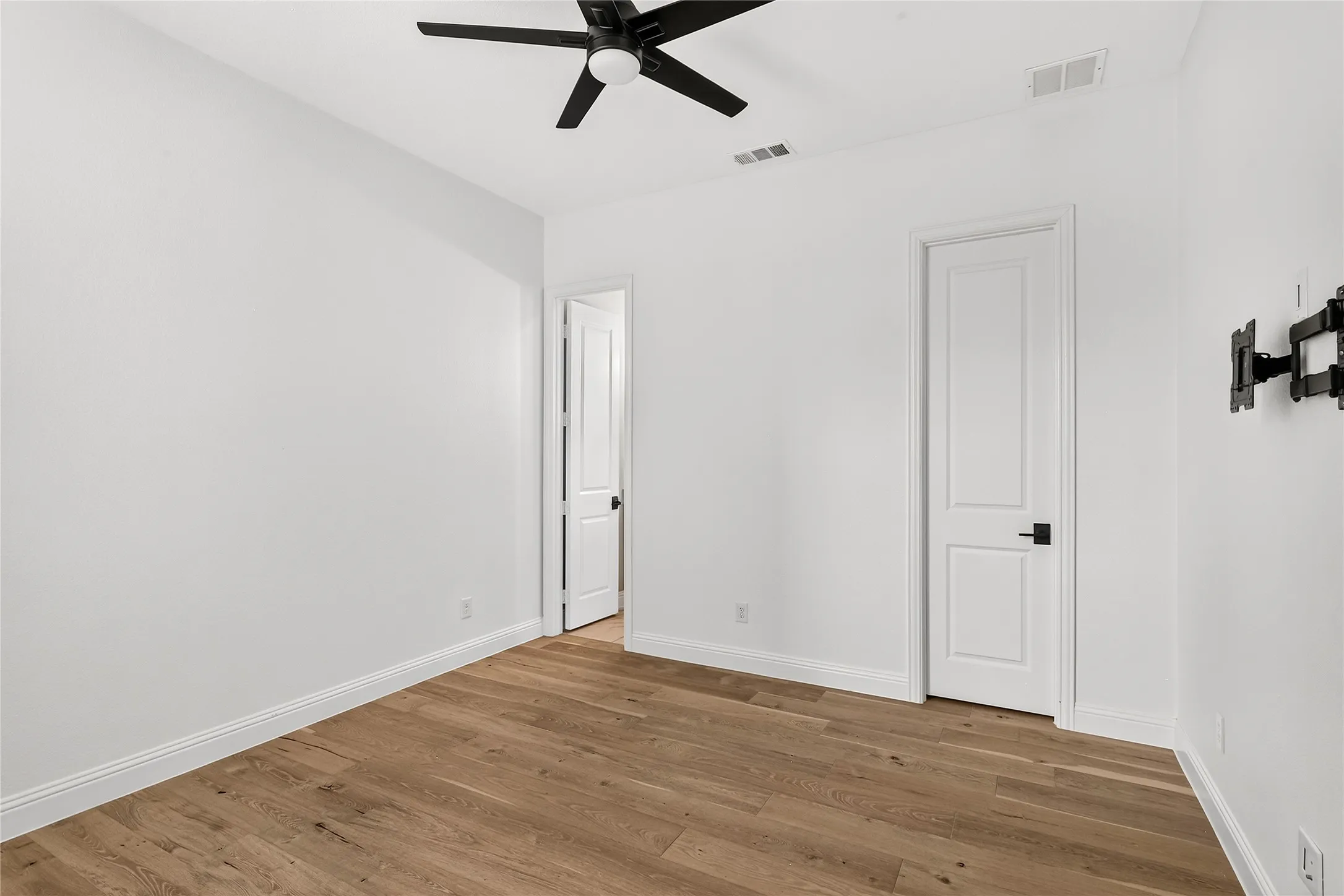 Bright secondary bedroom on the first floor with wide-plank hardwood flooring