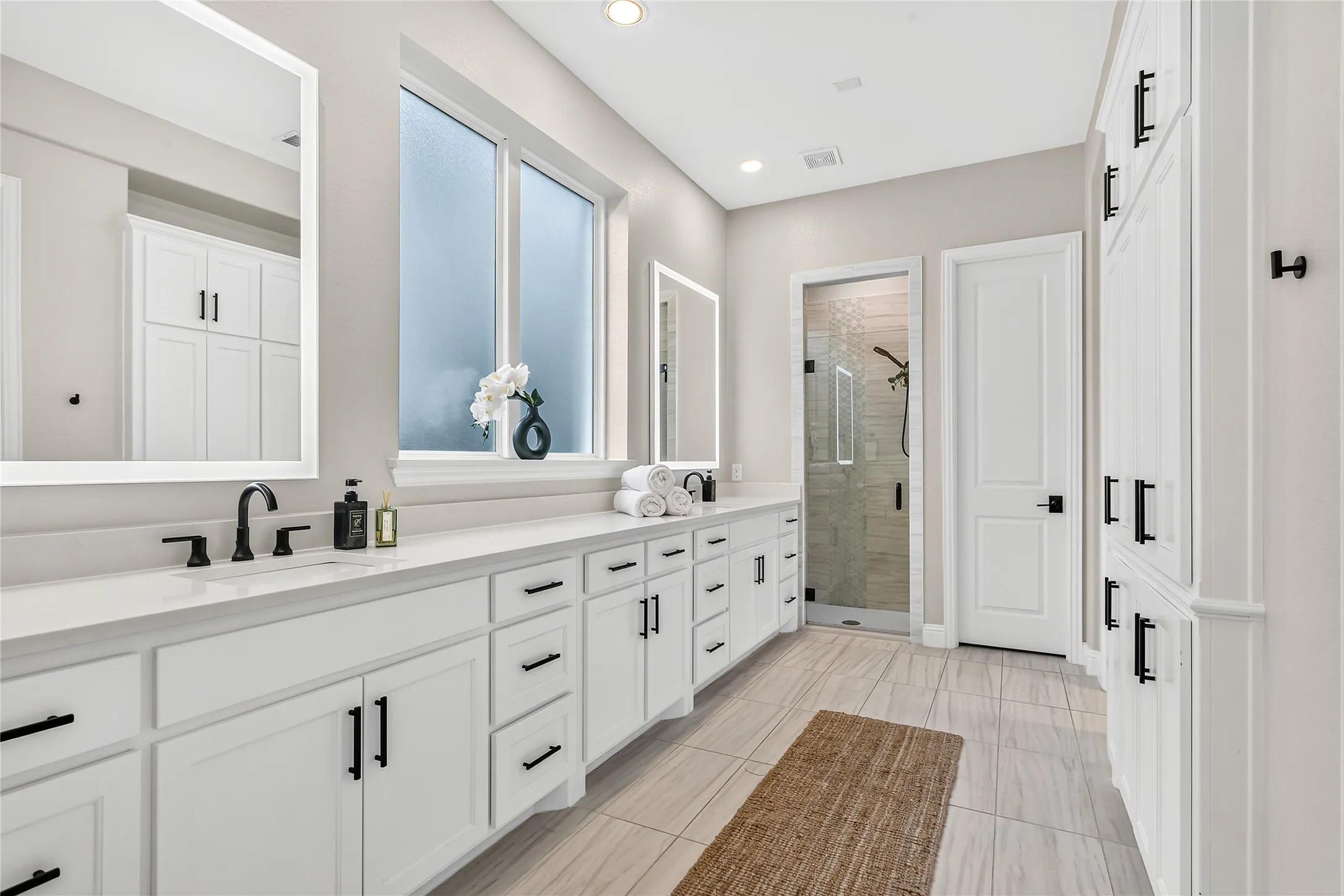 Spa-like primary bath with backlit LED mirrors and a large window that fills the space with natural light.