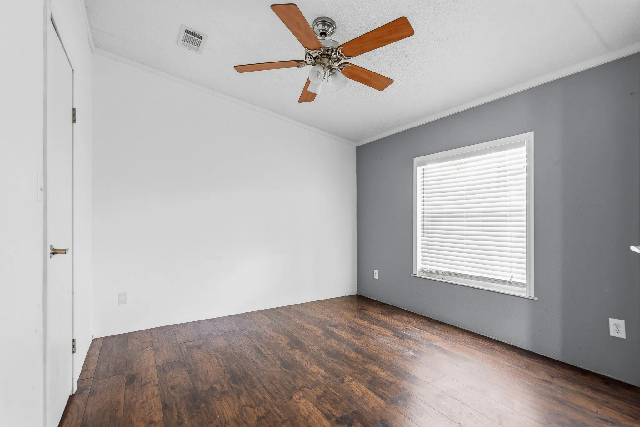 Wood-finish flooring, ceiling fan, white trim, and a window with blinds