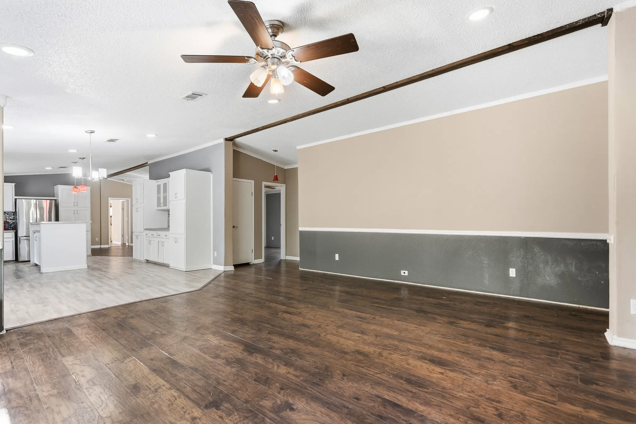 Wood-finish flooring, recessed lighting, ceiling fan, white cabinetry, and stainless steel appliances
