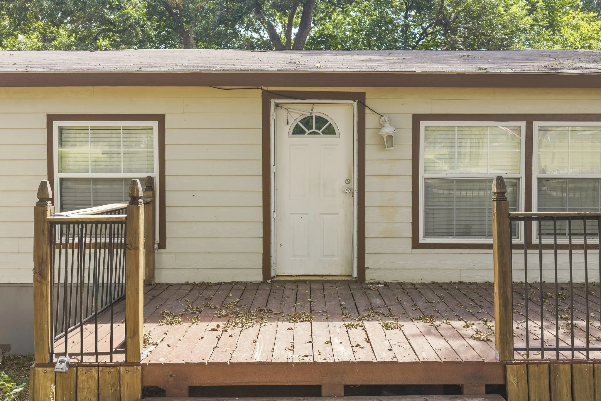 Front facade featuring horizontal siding, multiple windows, a main entry door with an arched transom, and a wood-finish deck with railing