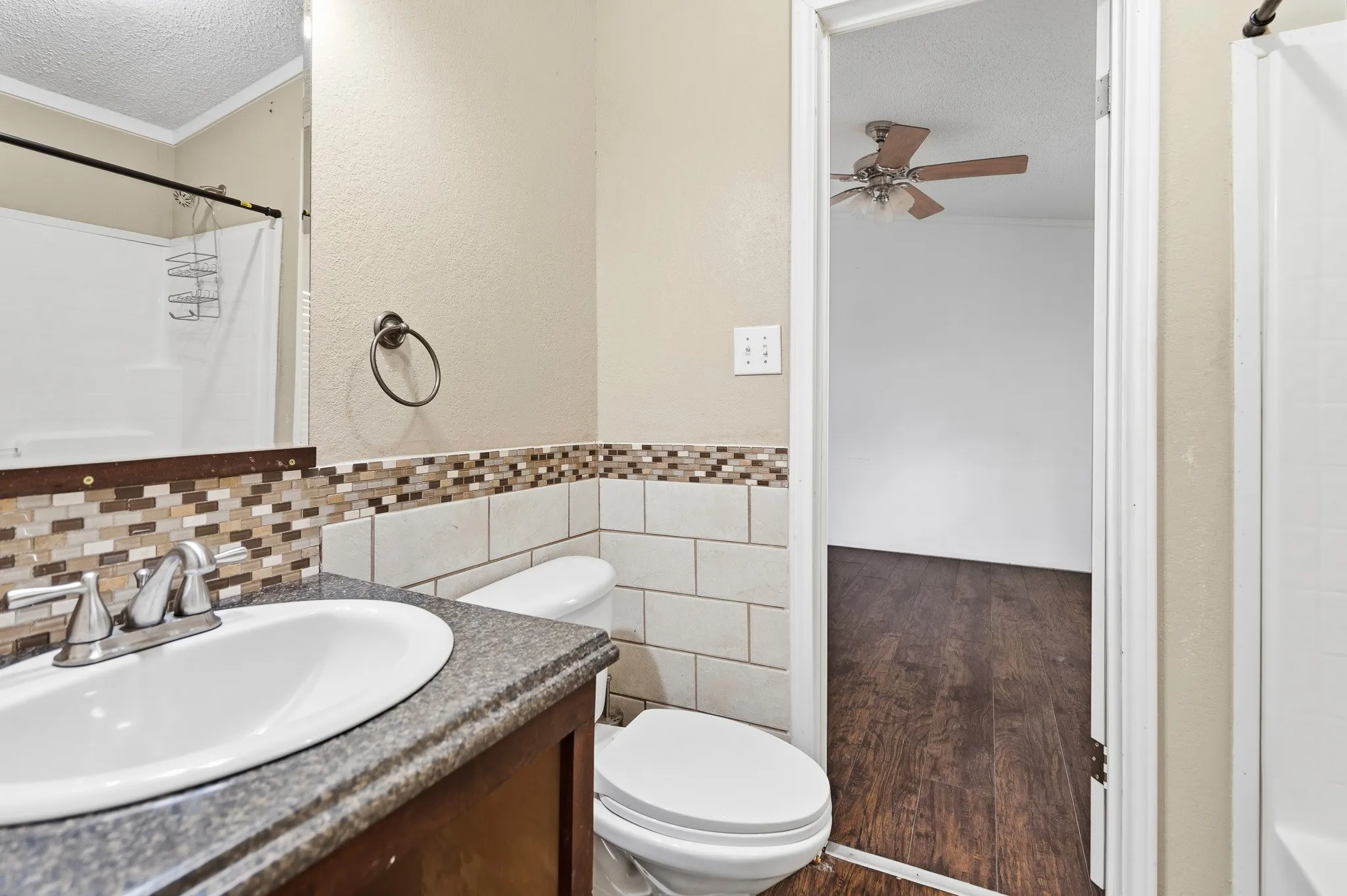 Vanity with a solid surface countertop, mosaic tile backsplash, and white subway tile wainscoting