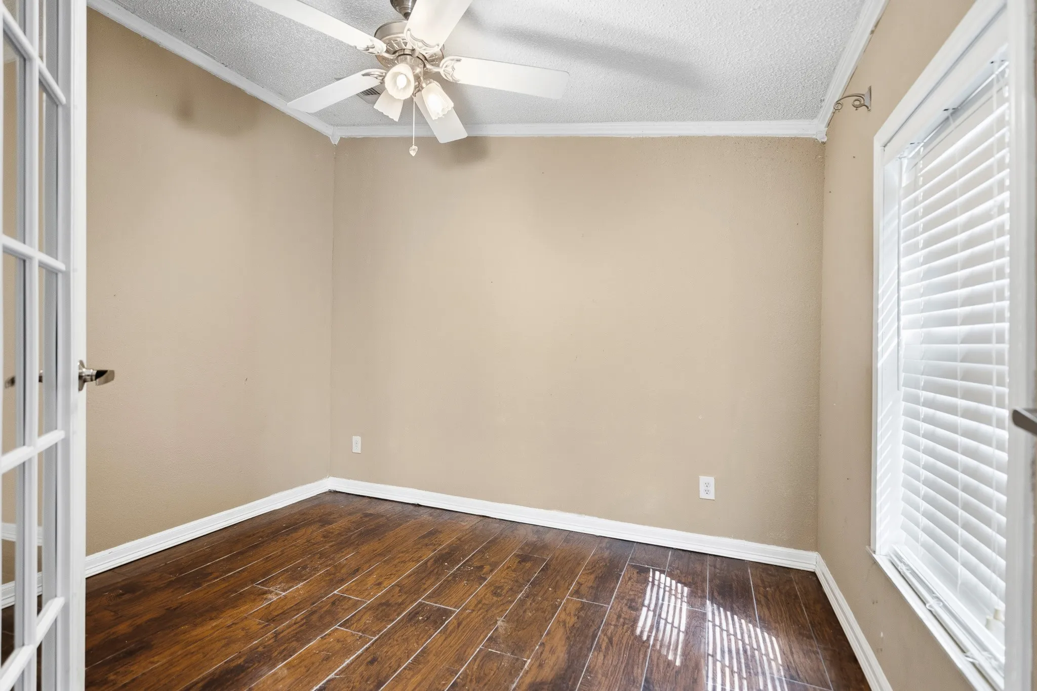 Wood-finish flooring, ceiling fan, white window blinds, and French doors