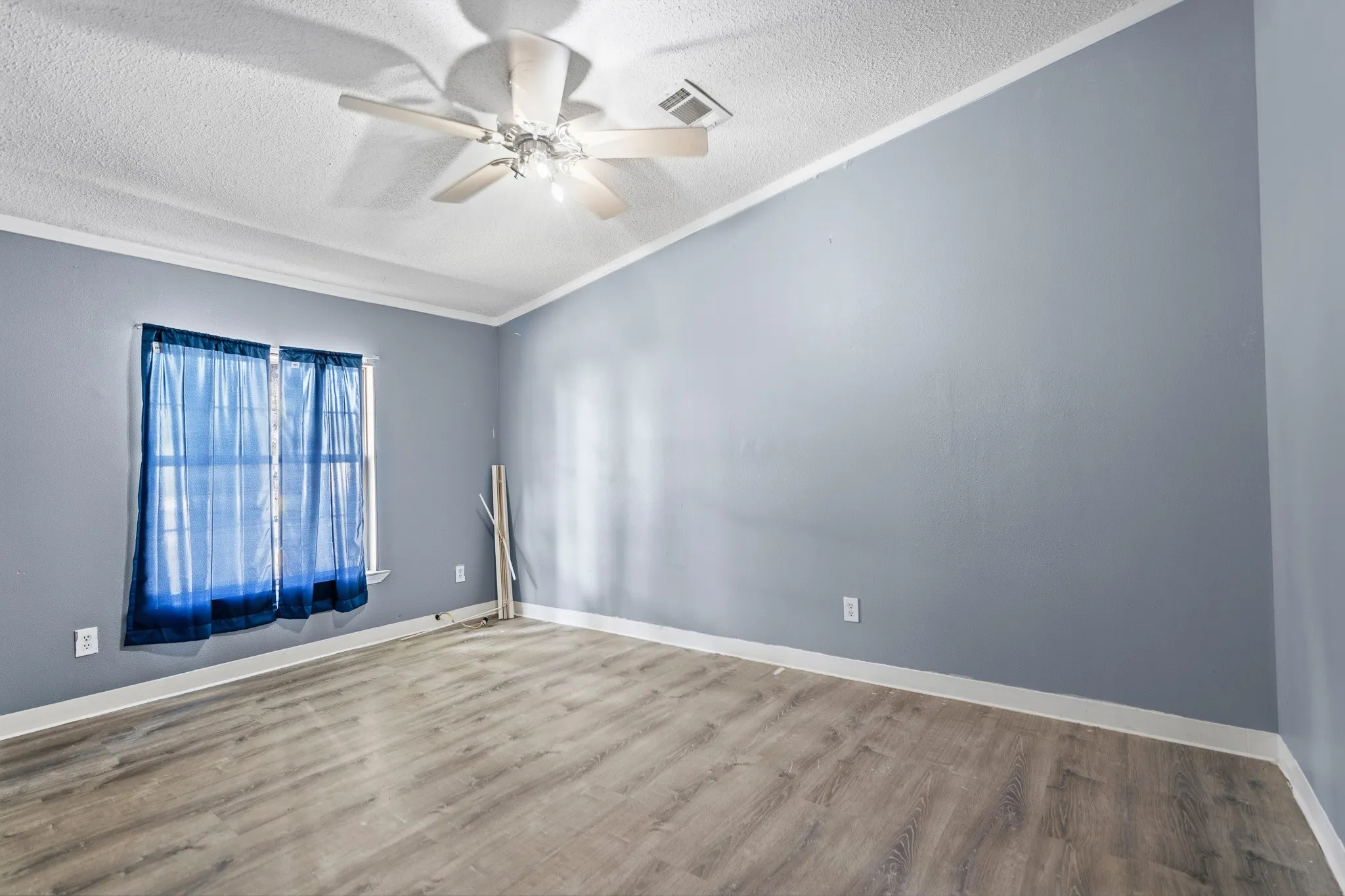 Wood-finish flooring, ceiling fan with integrated lighting, a double window, and crown molding