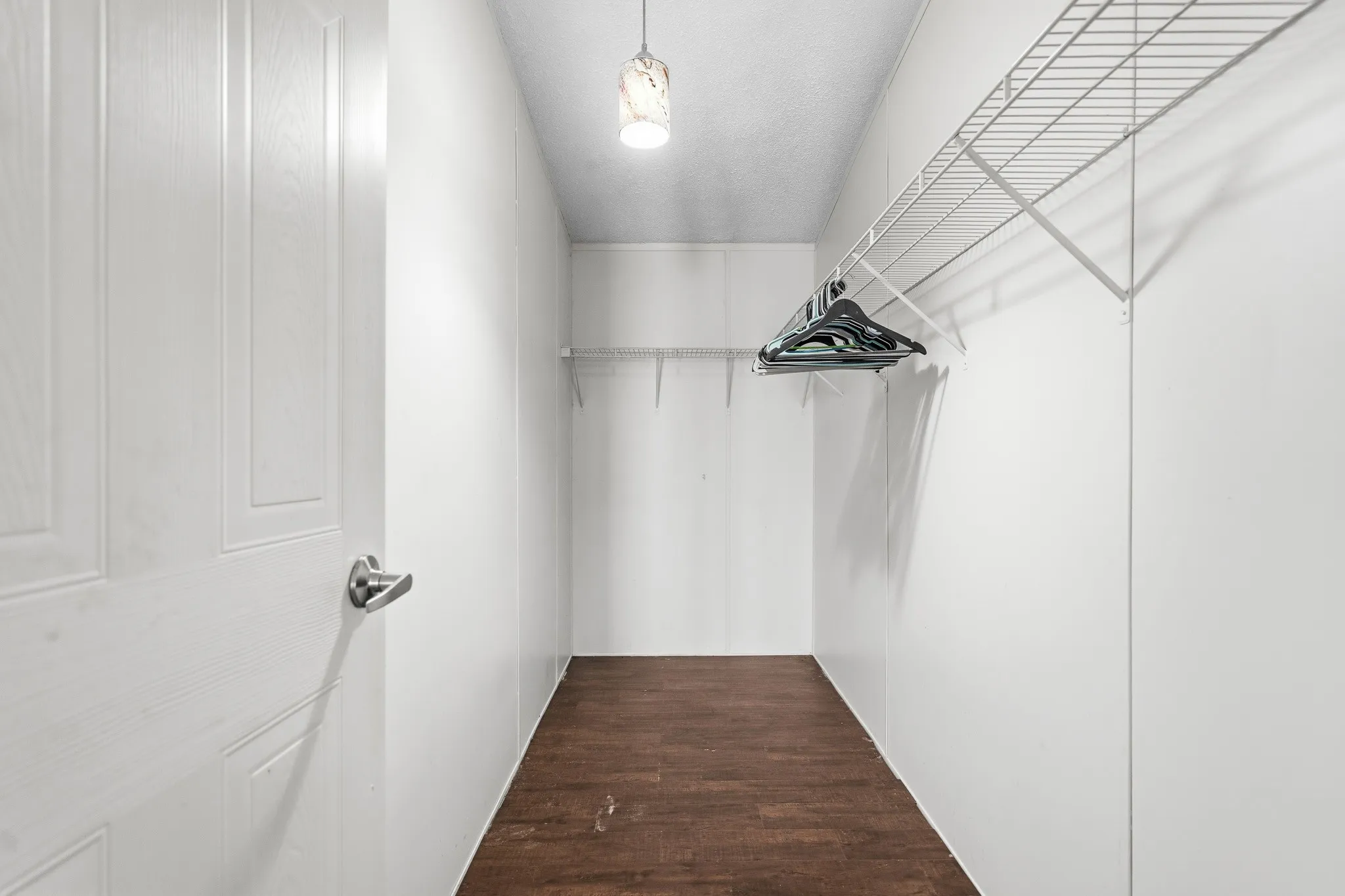 Walk-in closet featuring wood-finish flooring, white walls, and wire shelving