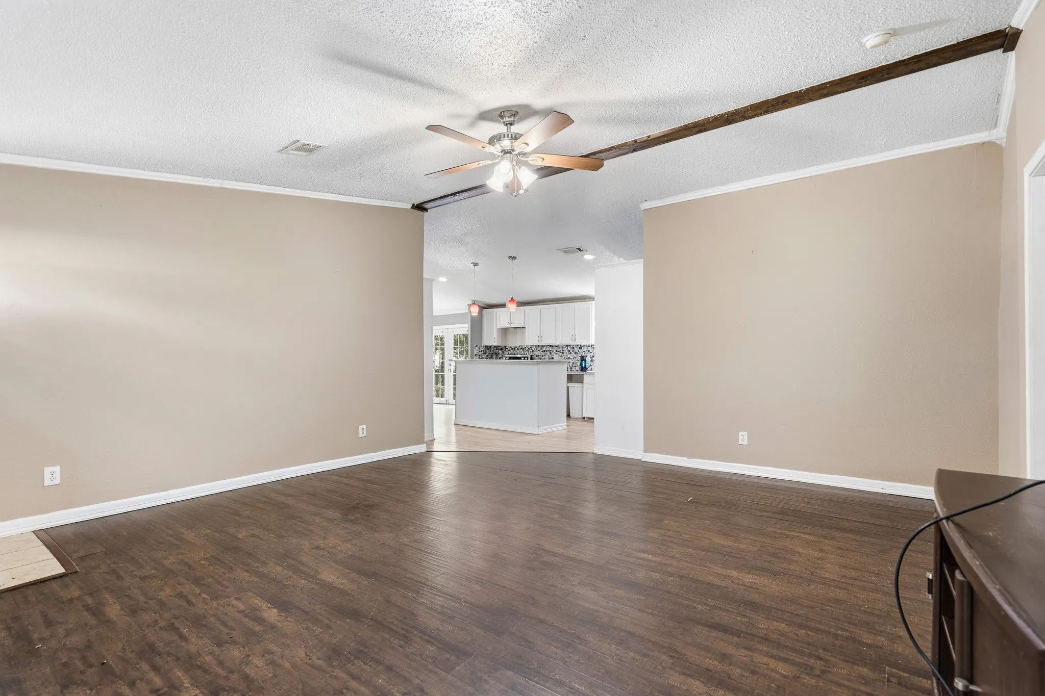 Spacious room with wood-finish flooring, a ceiling fan, and crown molding