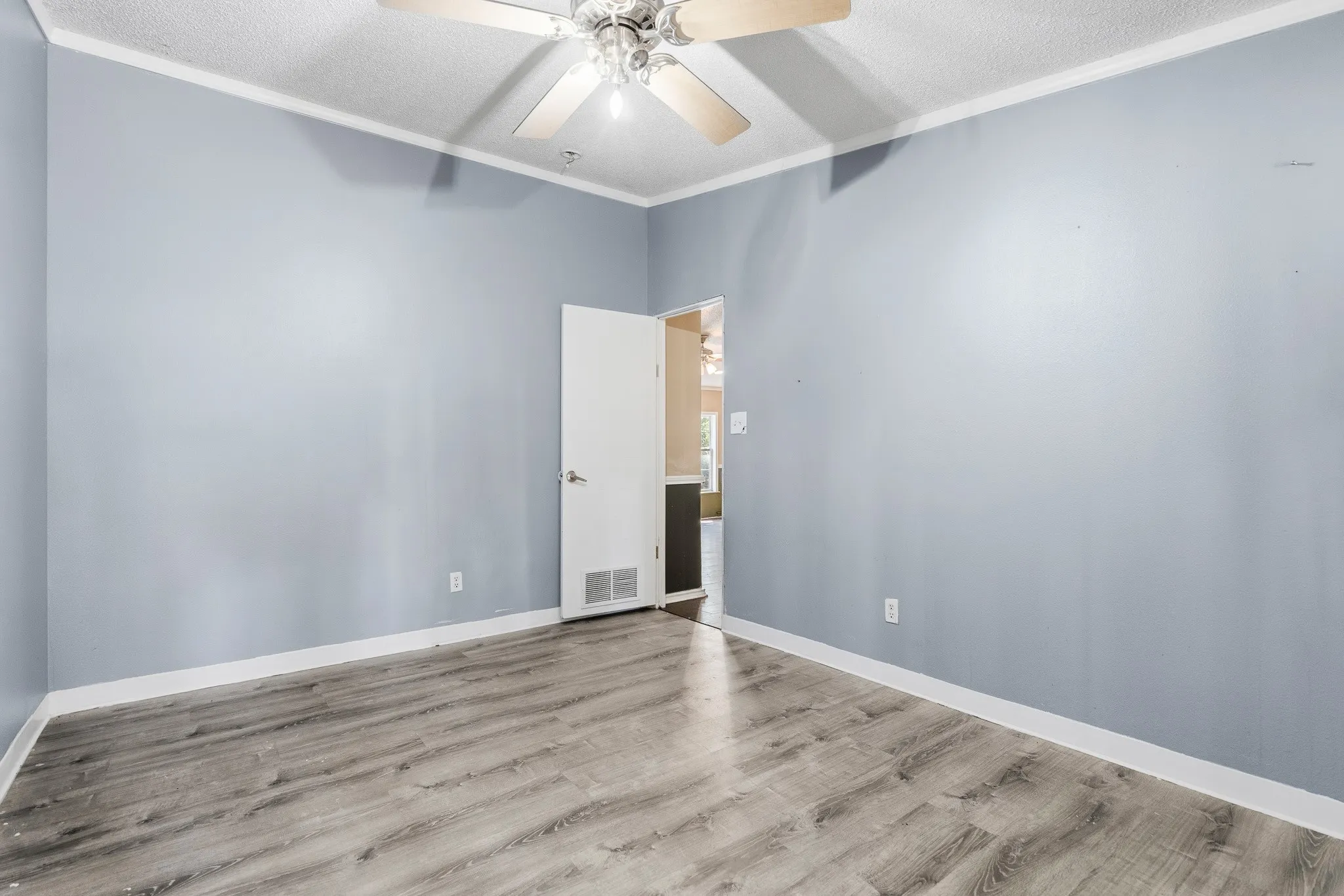 Wood-finish flooring, ceiling fan, white trim, and light blue walls