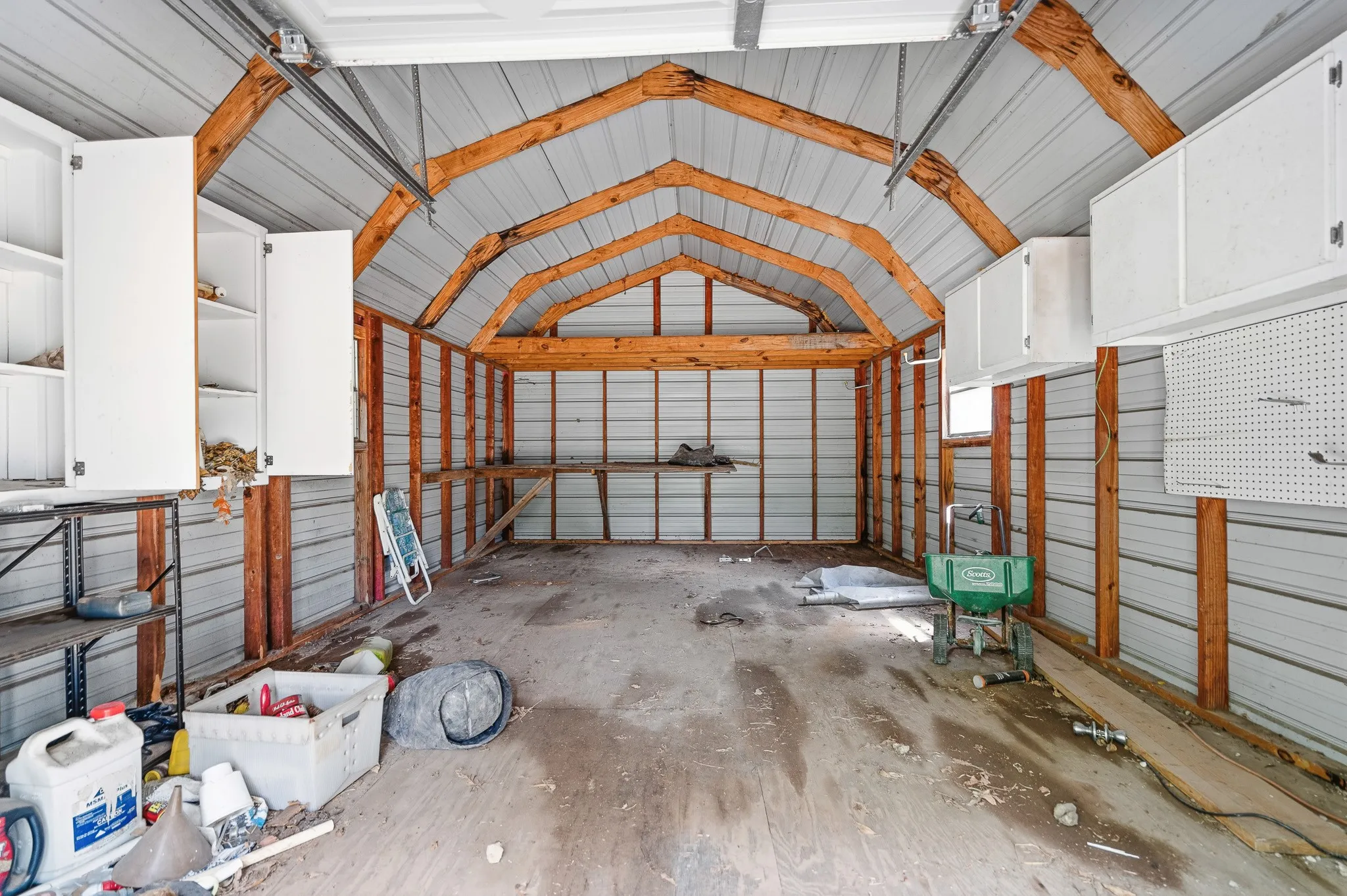 Metal-clad interior with exposed wood framing, integrated overhead cabinetry, and built-in shelving