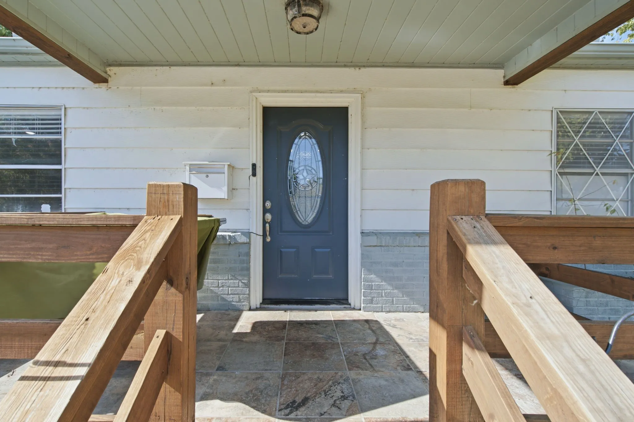 Front entry with a dark-paneled door featuring an oval decorative glass insert, complemented by a wall-mounted mailbox and a decorative light fixture