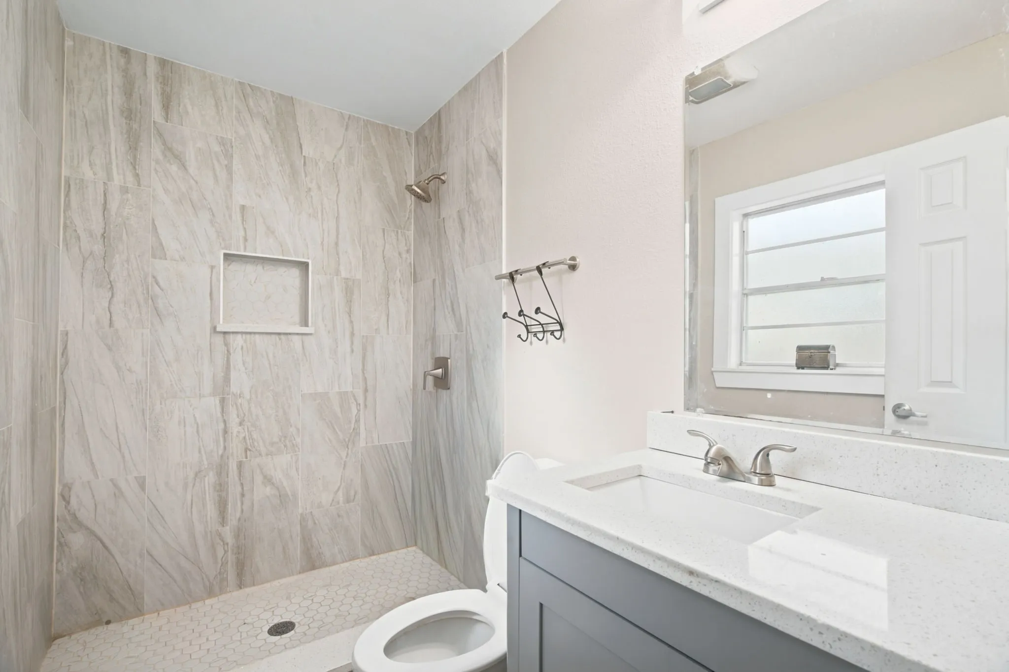 Tiled shower with a built-in niche and hexagonal floor tiles