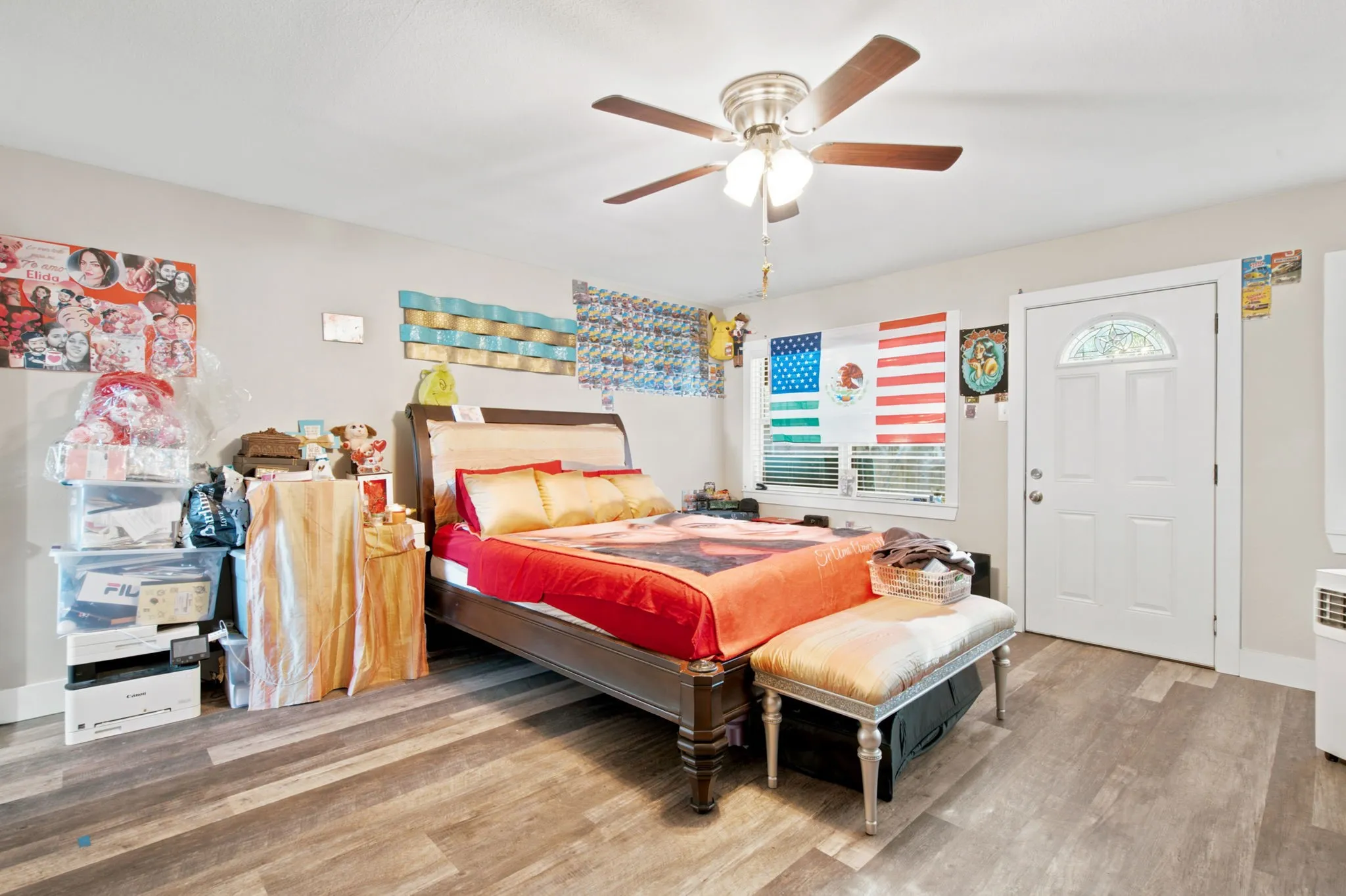 Wood-finish flooring, ceiling fan with integrated lighting, and a white paneled door with decorative glass insert