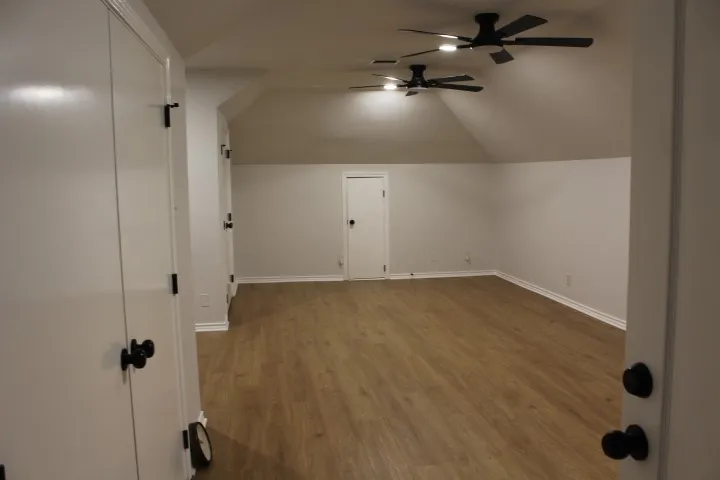 Vaulted ceilings, wood-finish flooring, white walls, multiple ceiling fans, and built-in storage