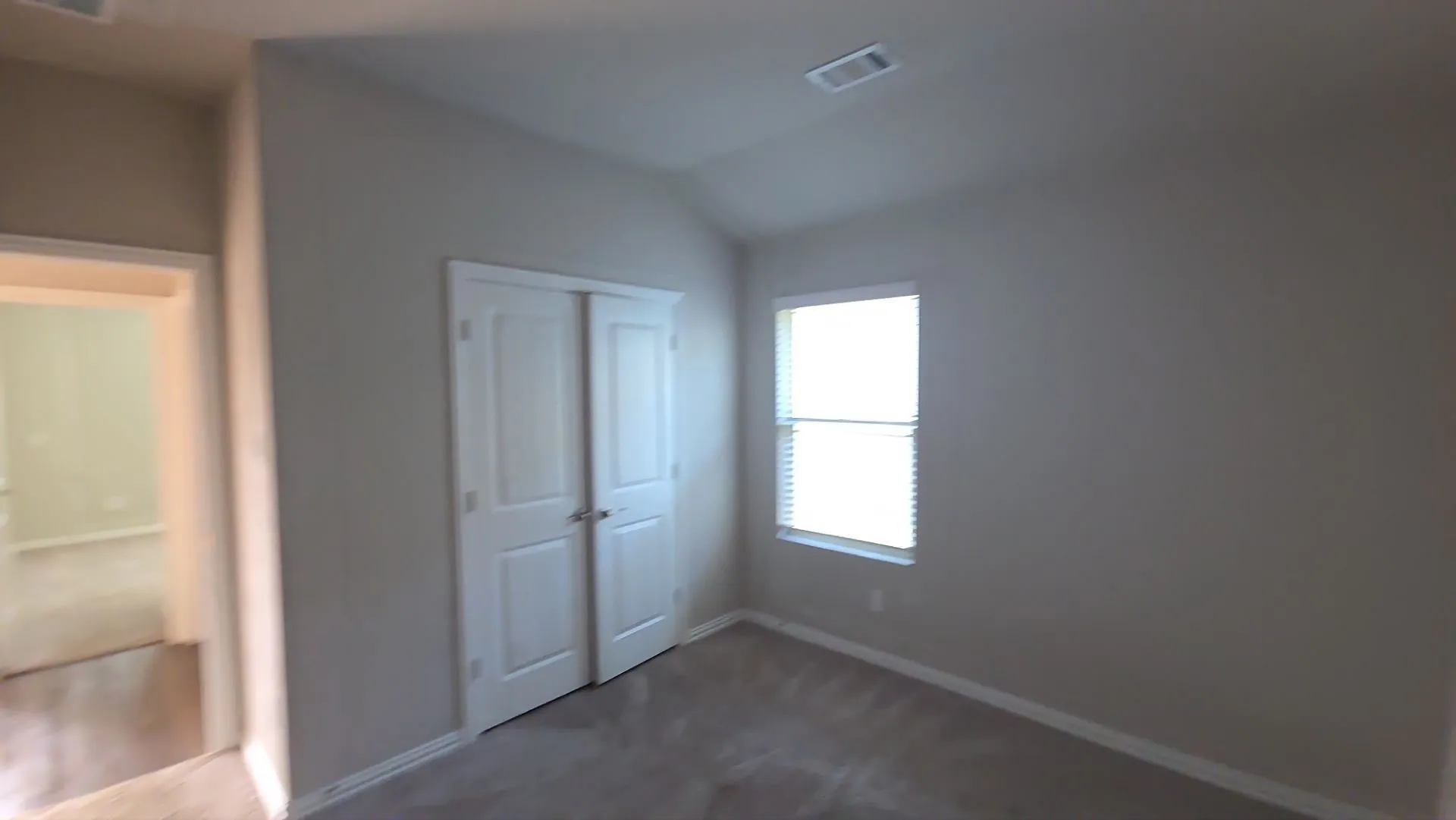 Carpeted room with a single window featuring blinds, a double-door closet, and vaulted ceiling
