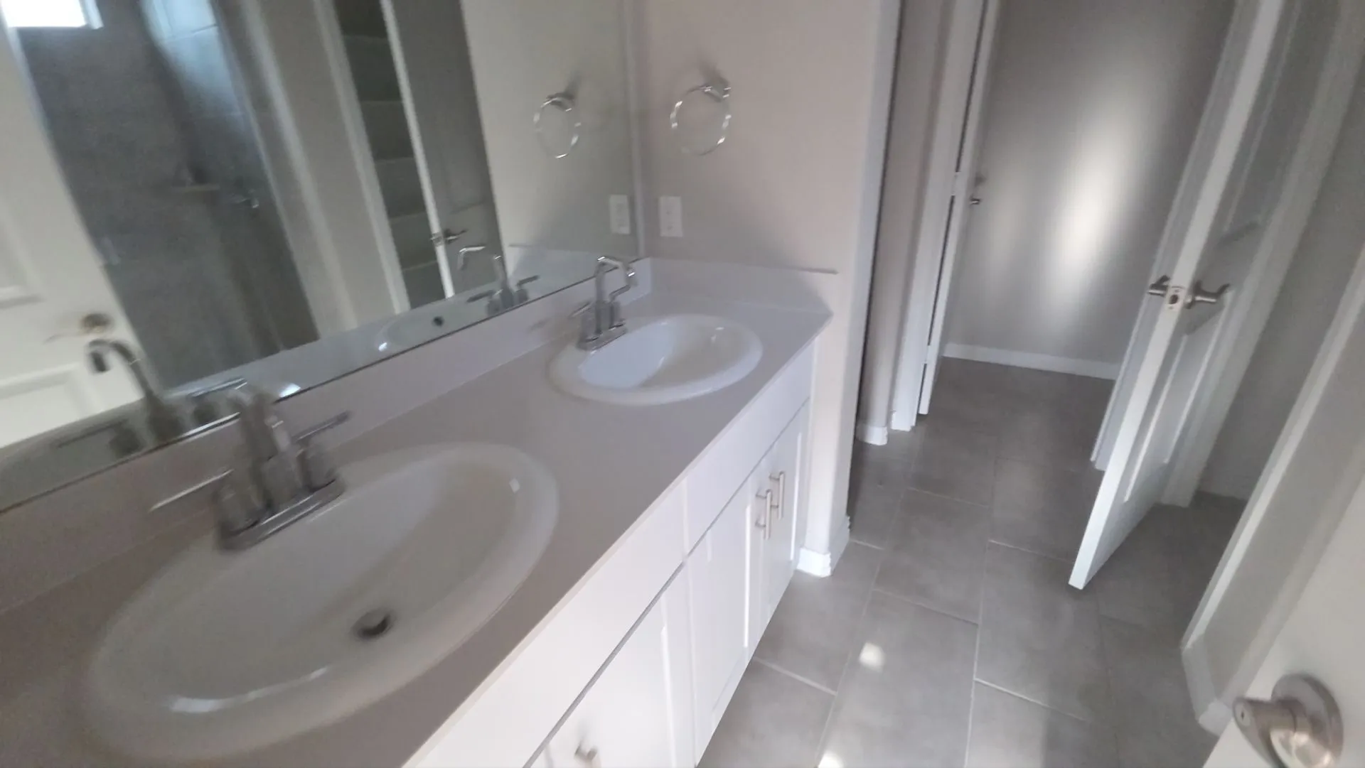Dual vanity with integrated sinks, chrome fixtures, and a large wall-mounted mirror