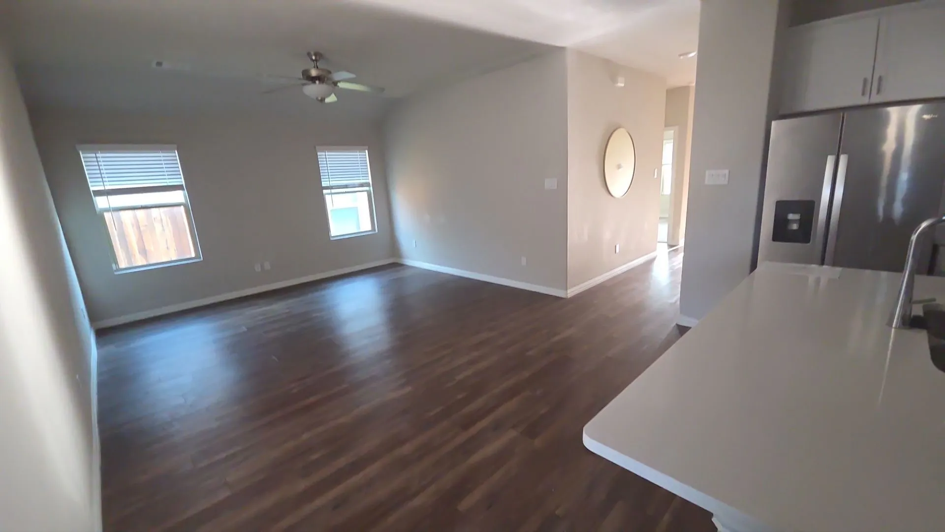 Open-concept living space featuring wood-finish flooring, a ceiling fan, and multiple windows