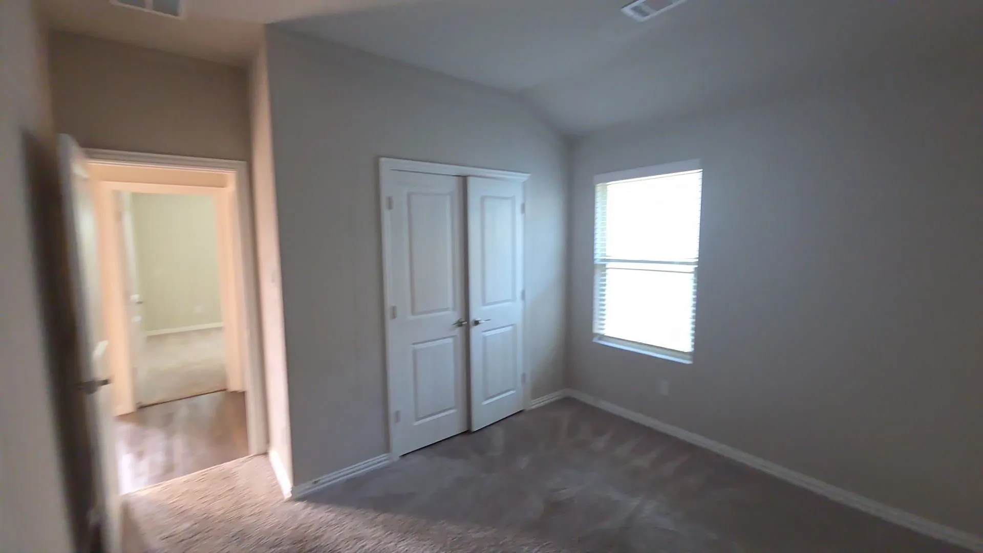 Carpeted room featuring a window with blinds, a double-door closet, and neutral-toned walls