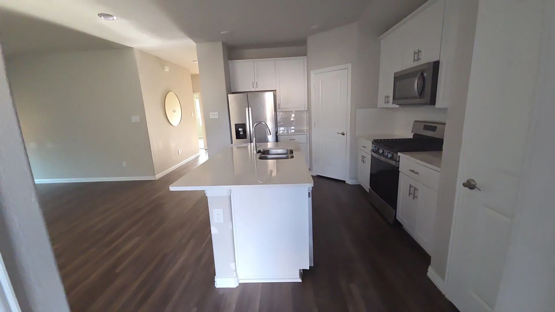 Kitchen featuring white cabinetry, stainless steel appliances, a center island with sink, and light-colored countertops