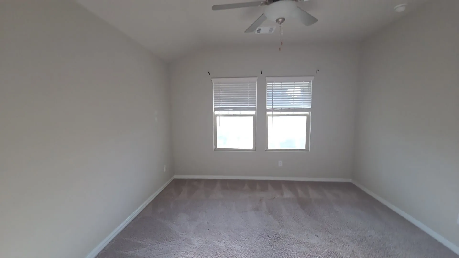 Carpeted room with vaulted ceilings and a ceiling fan