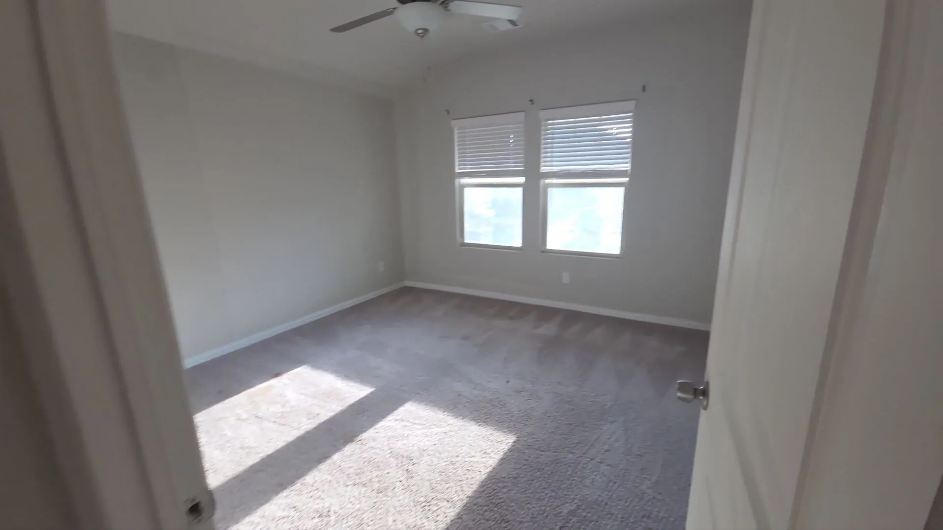 Carpeted flooring, dual windows with blinds, and a ceiling fan
