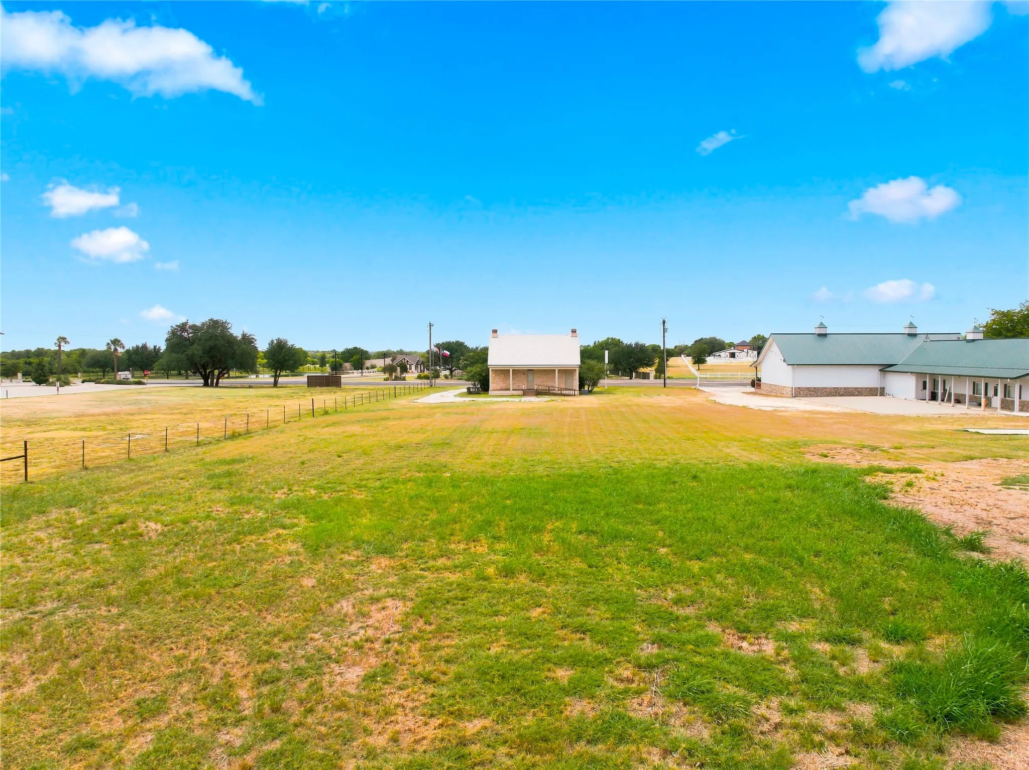 Expansive grounds featuring a perimeter fence and mature trees