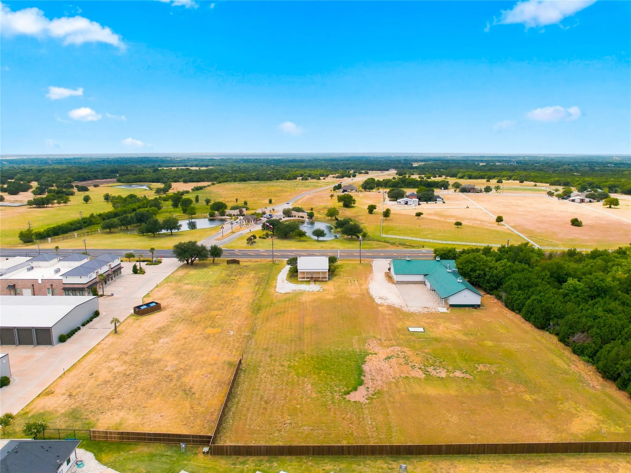 Expansive land parcel featuring open fields, a body of water, and surrounding green landscapes