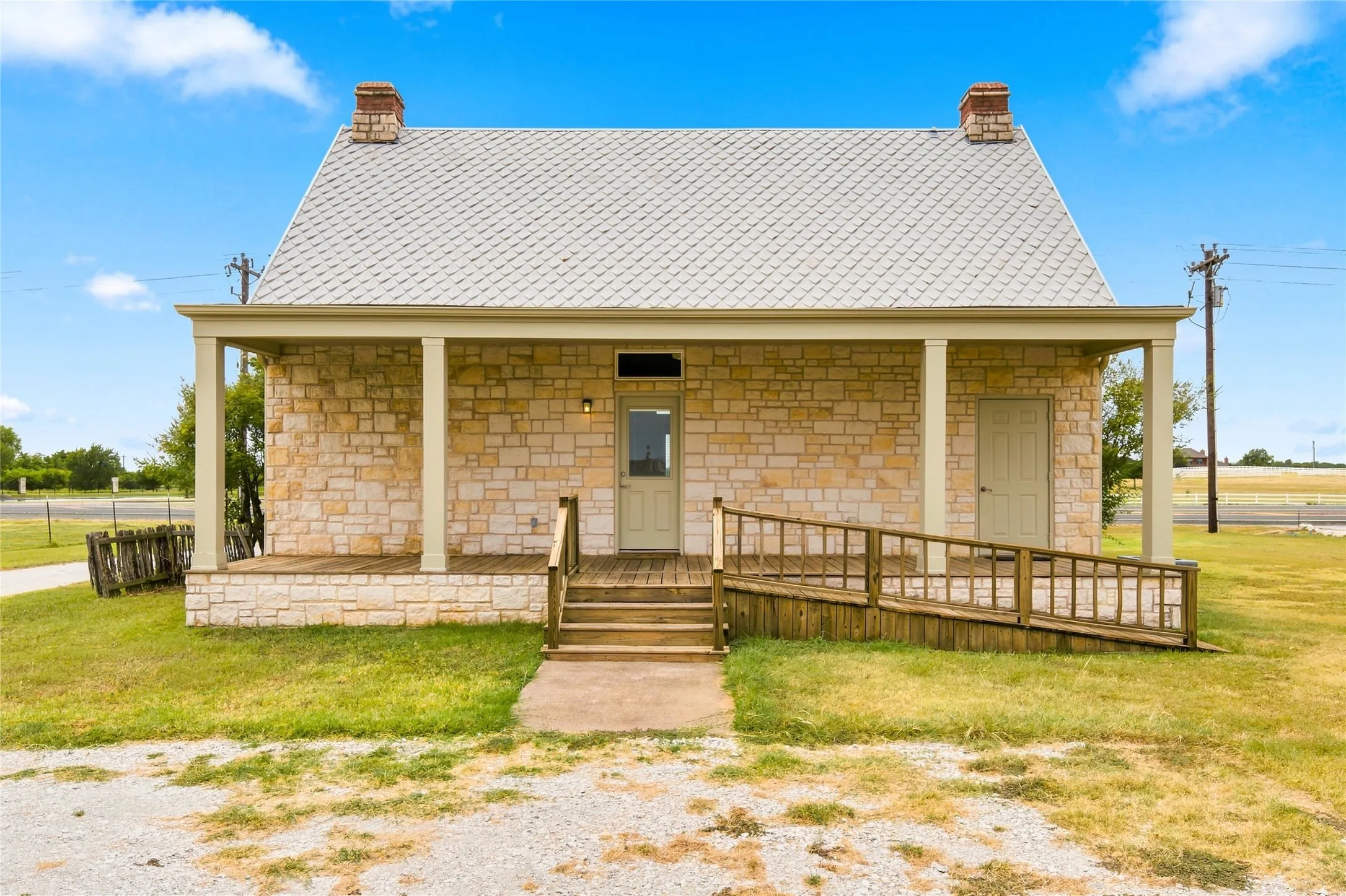 Stone facade with a covered porch, wood plank decking, and a wood ramp