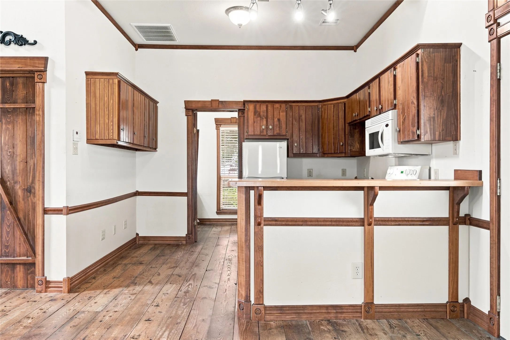 Wood-finish flooring, accent trim, wood cabinetry, and recessed lighting