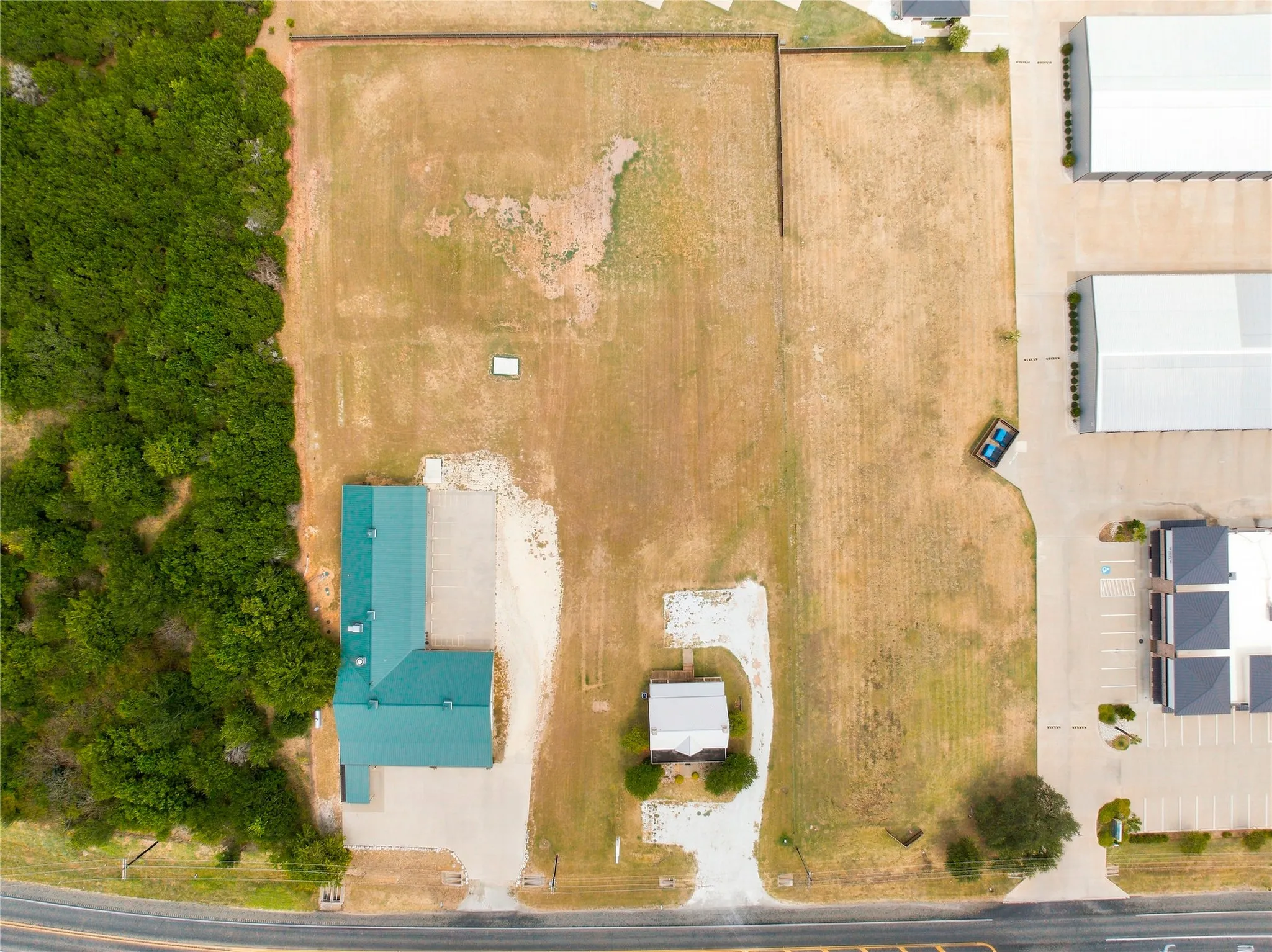 Commercial building with a green roof, expansive land, and partial tree coverage