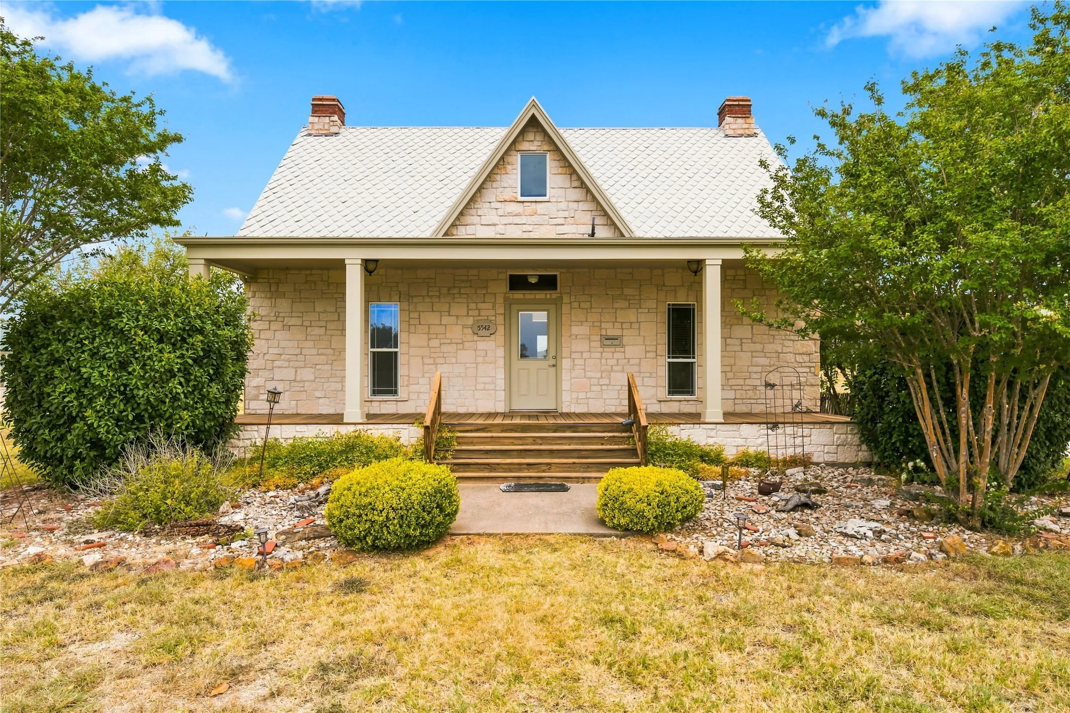 Stone exterior with a covered porch, wood stairs, and a pitched roof