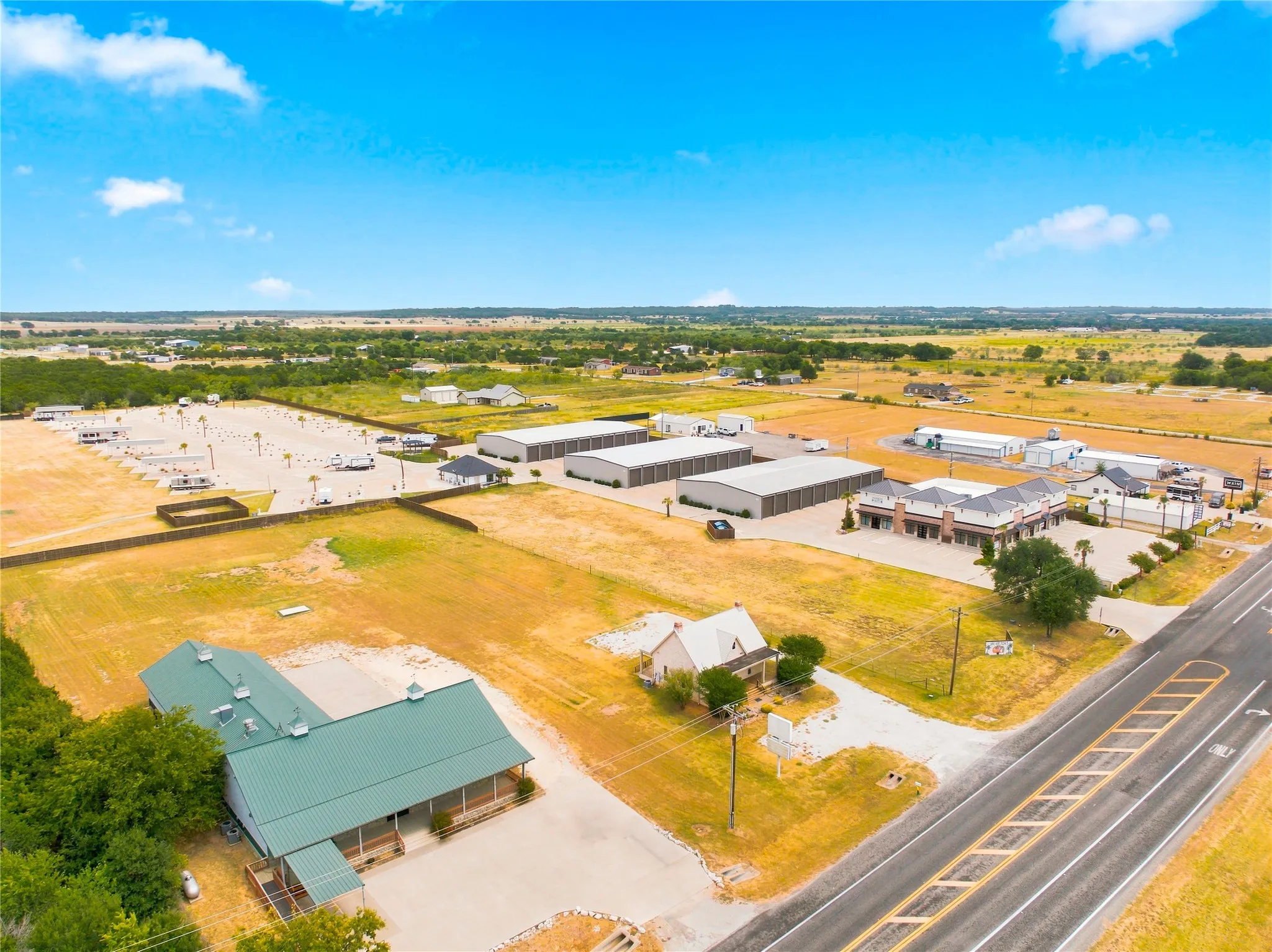 Expansive property featuring multiple buildings, paved parking areas, and a visible roadway