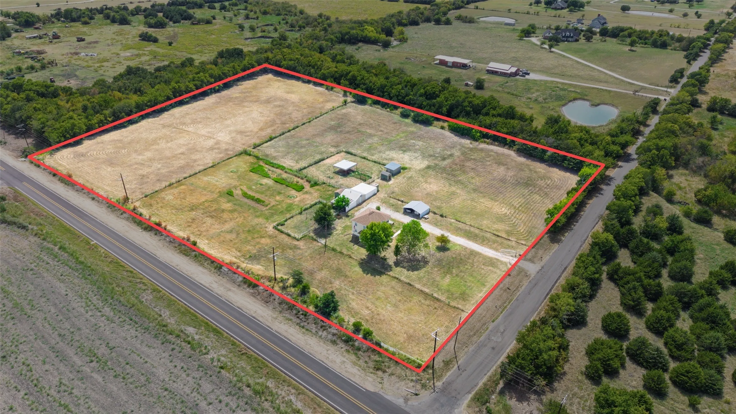 Expansive rural property featuring a primary residence, multiple outbuildings, and a perimeter fence