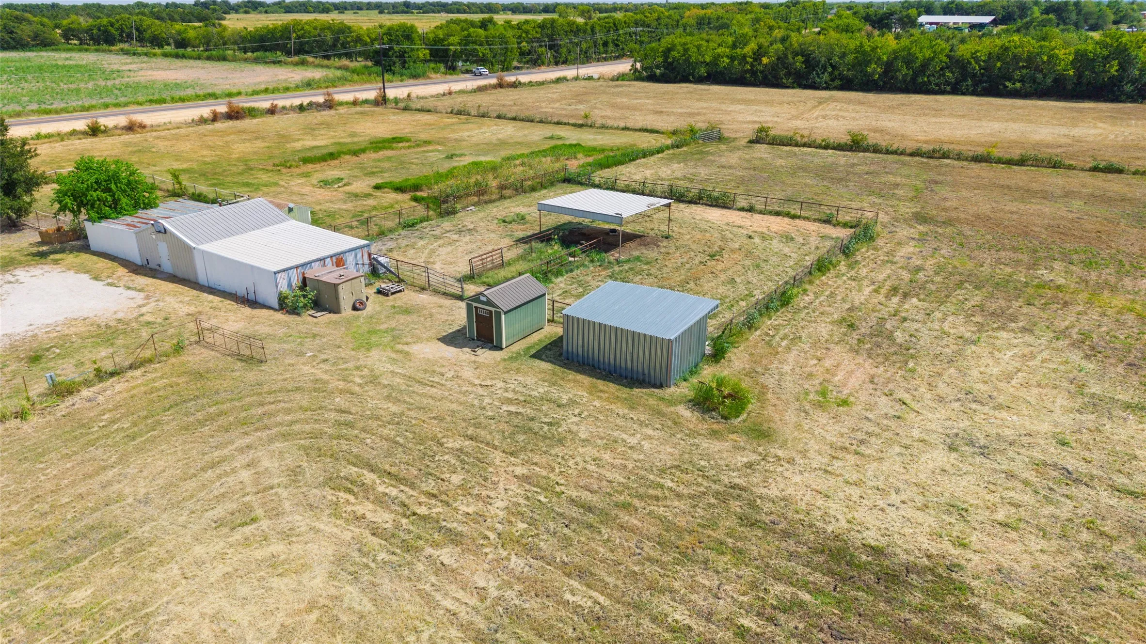Expansive grounds featuring multiple outbuildings, fenced enclosures, and a metal-roofed structure
