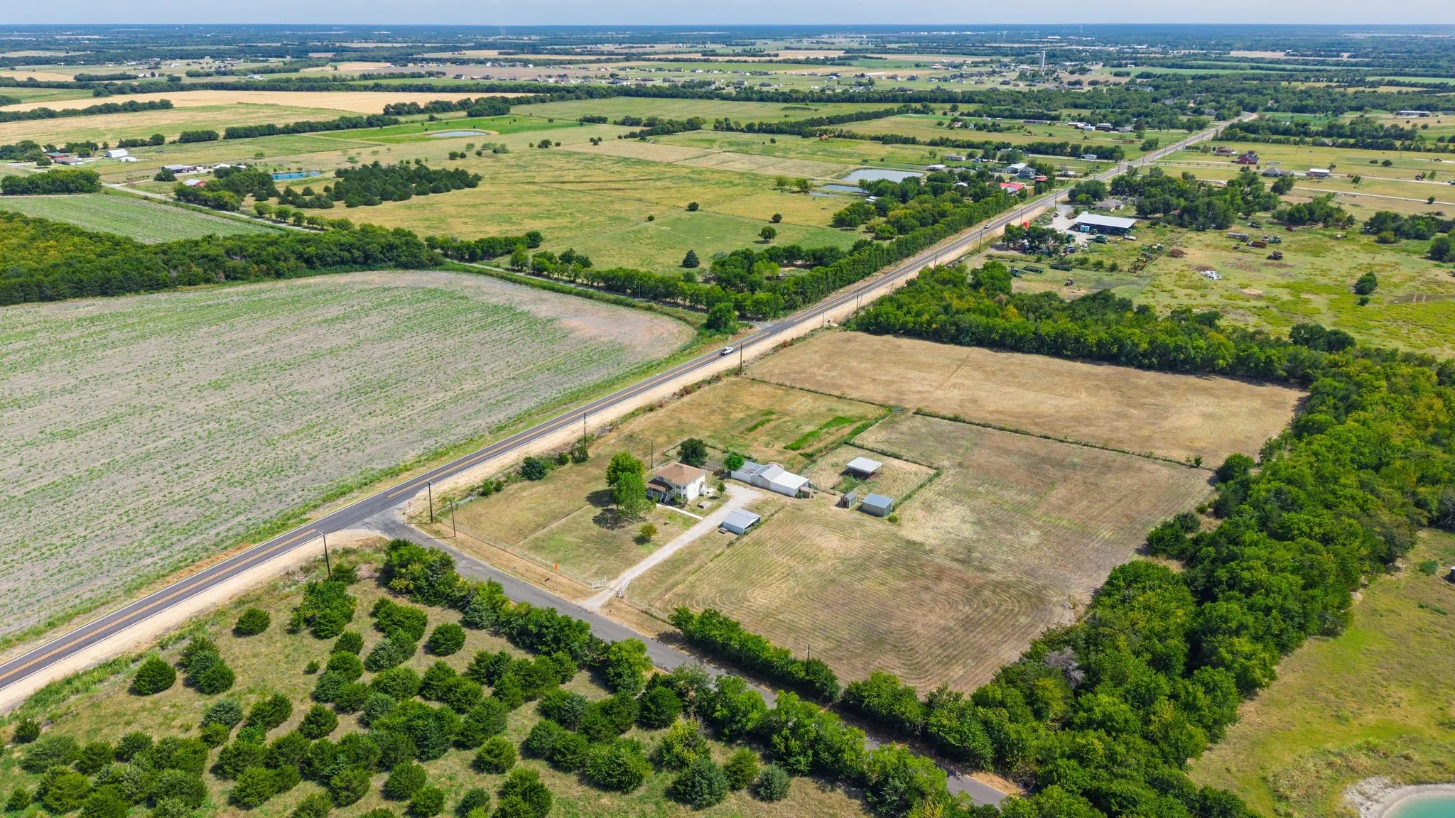 Expansive rural property featuring a main residence, multiple outbuildings, and cultivated land