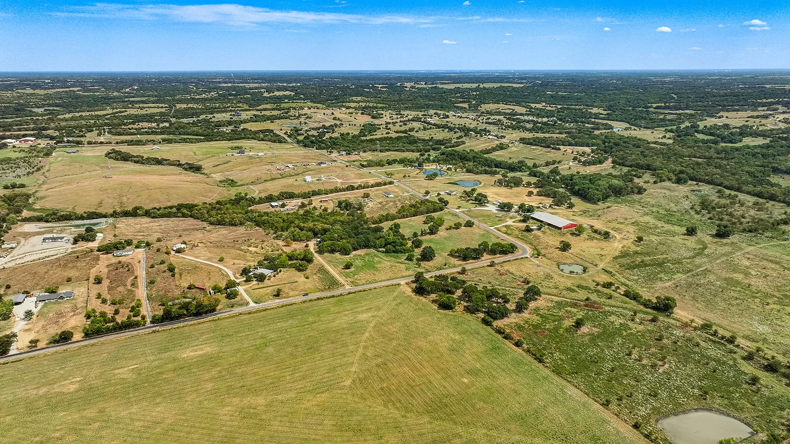 Expansive rural landscape featuring scattered homes, mature trees, and multiple small ponds