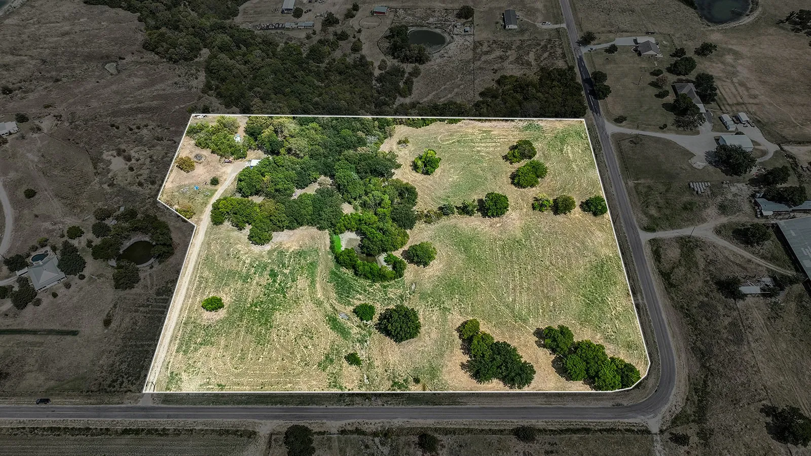 Expansive land parcel featuring a mix of open terrain and mature tree clusters