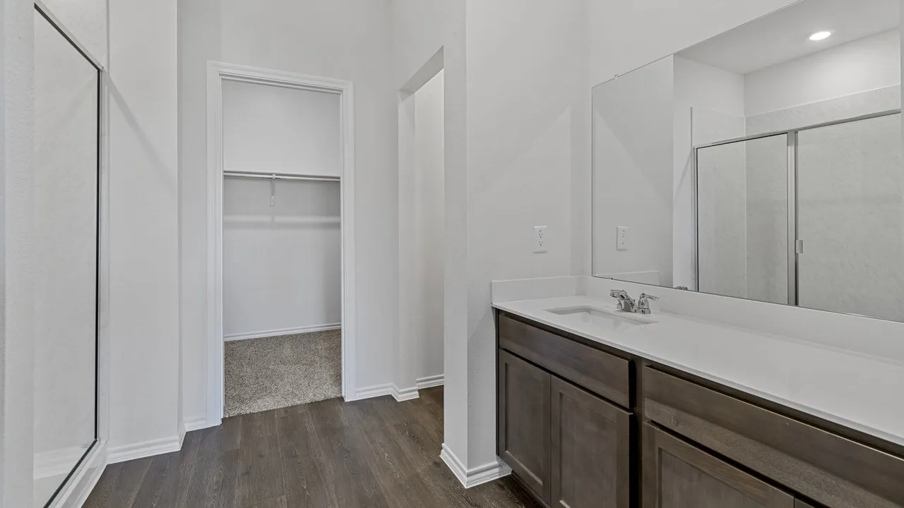 Dual vanity with a white countertop and undermount sink, wood-finish flooring, and a walk-in shower with a glass enclosure