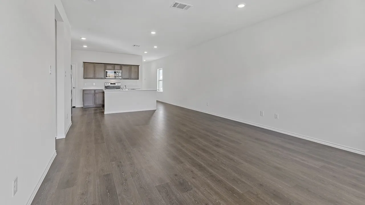Open-concept living area with wood-finish flooring, recessed lighting, and a kitchen island with integrated sink