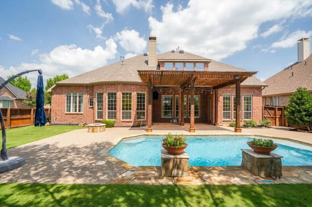 Rear exterior view showing brick home, covered patio & pool
