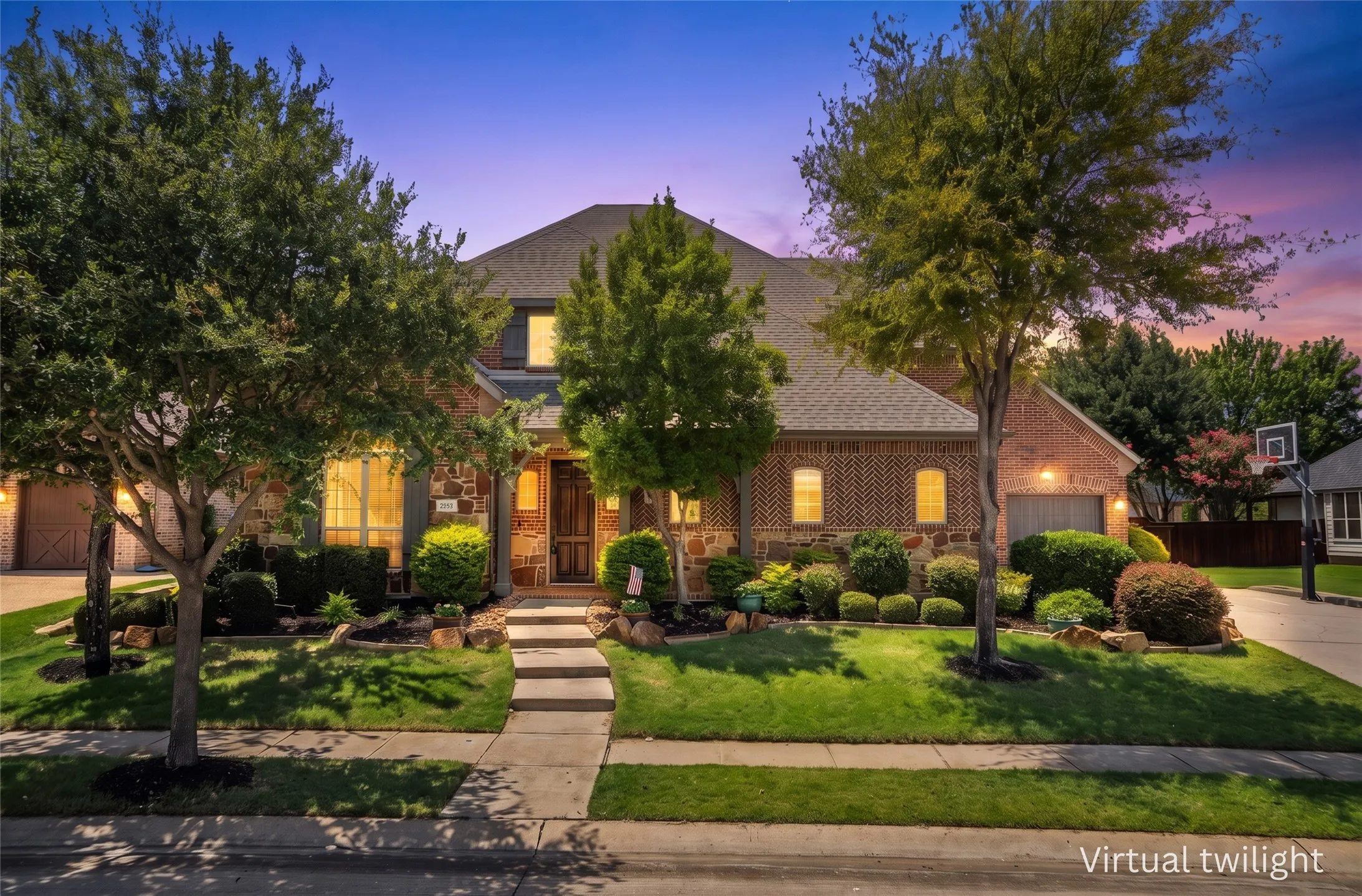 Grand front exterior view showcasing brick façade, manicured landscaping & stately curb appeal