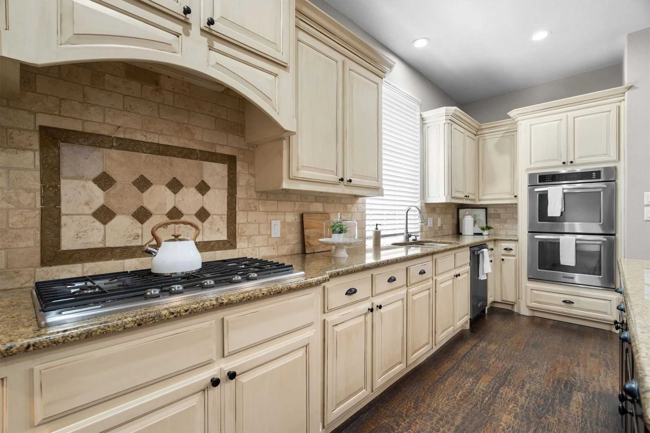 Kitchen cooktop detail with custom hood vent and decorative backsplash