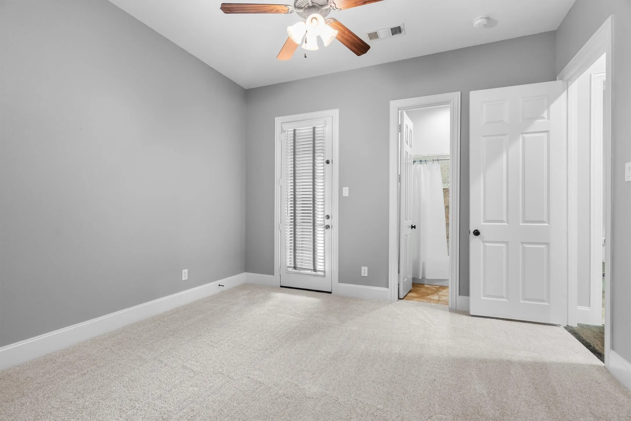 Secondary bedroom with French door entry, ceiling fan & neutral carpet