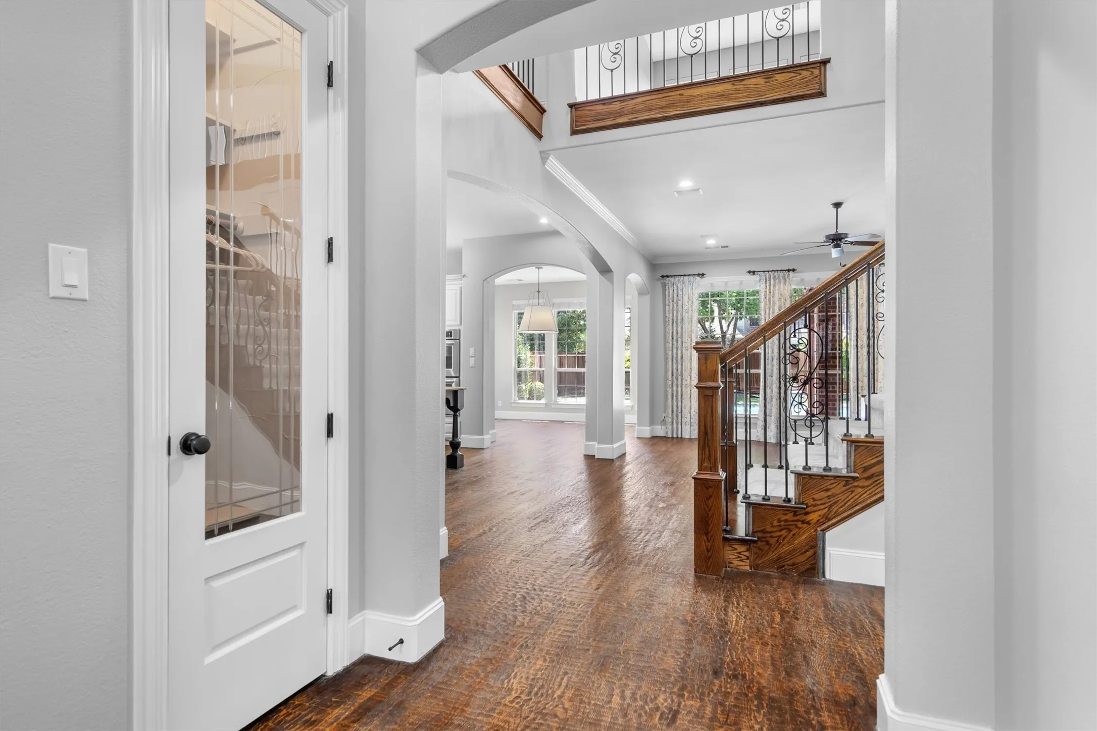 Elegant foyer view leading into open-concept living areas with wood staircase